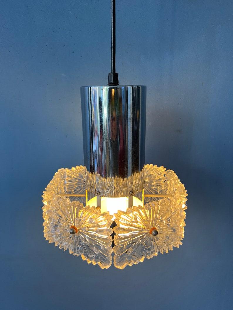 Lampada a sospensione di metà secolo con paralume in cristallo. La luce si riflette piacevolmente attraverso il rilievo grezzo degli elementi in vetro. La lampada richiede una lampadina E27/26 (standard).

Informazioni aggiuntive:
Materiali: Vetro,