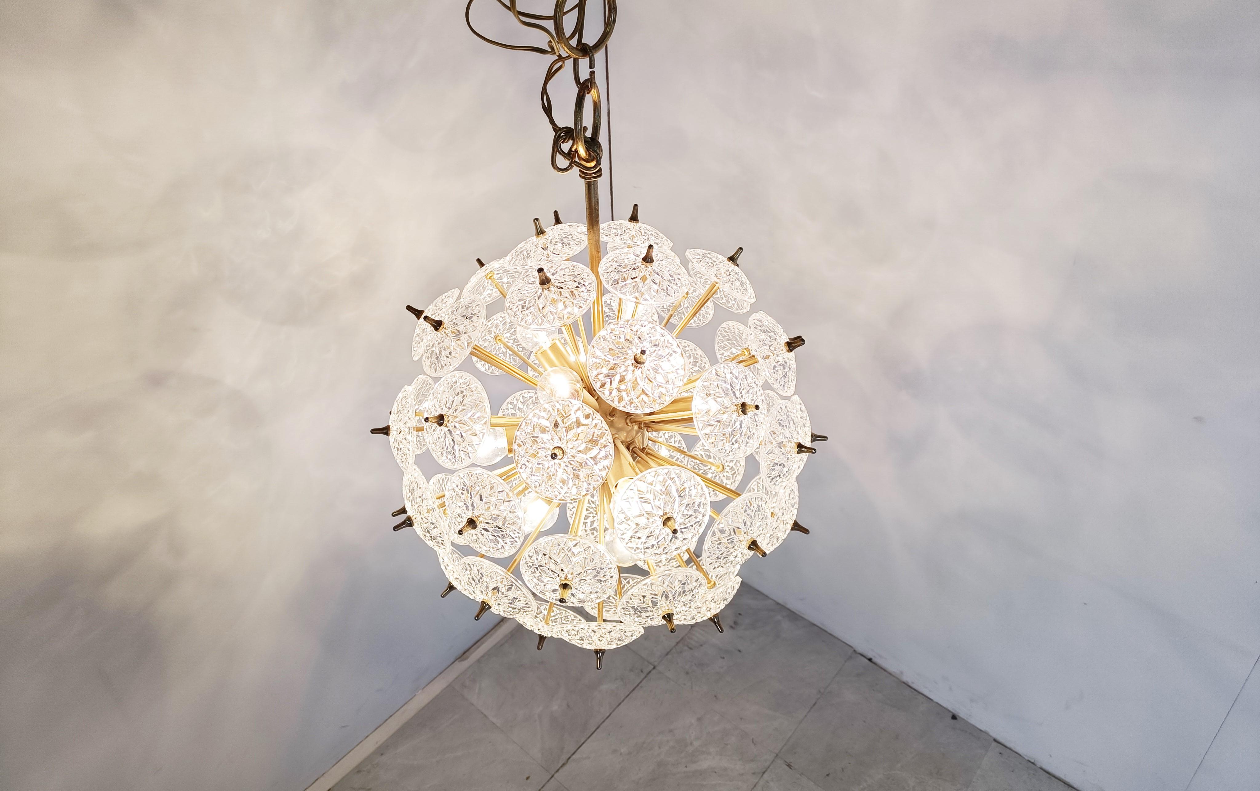 Impressive brass and crystal sputnik chandelier.

The crystals are made by the renowned belgium glass company Val Saint Lambert.

The chandelier has 12 lightpoints that can be used with regular E14 candle light bulbs.

These chandeliers are