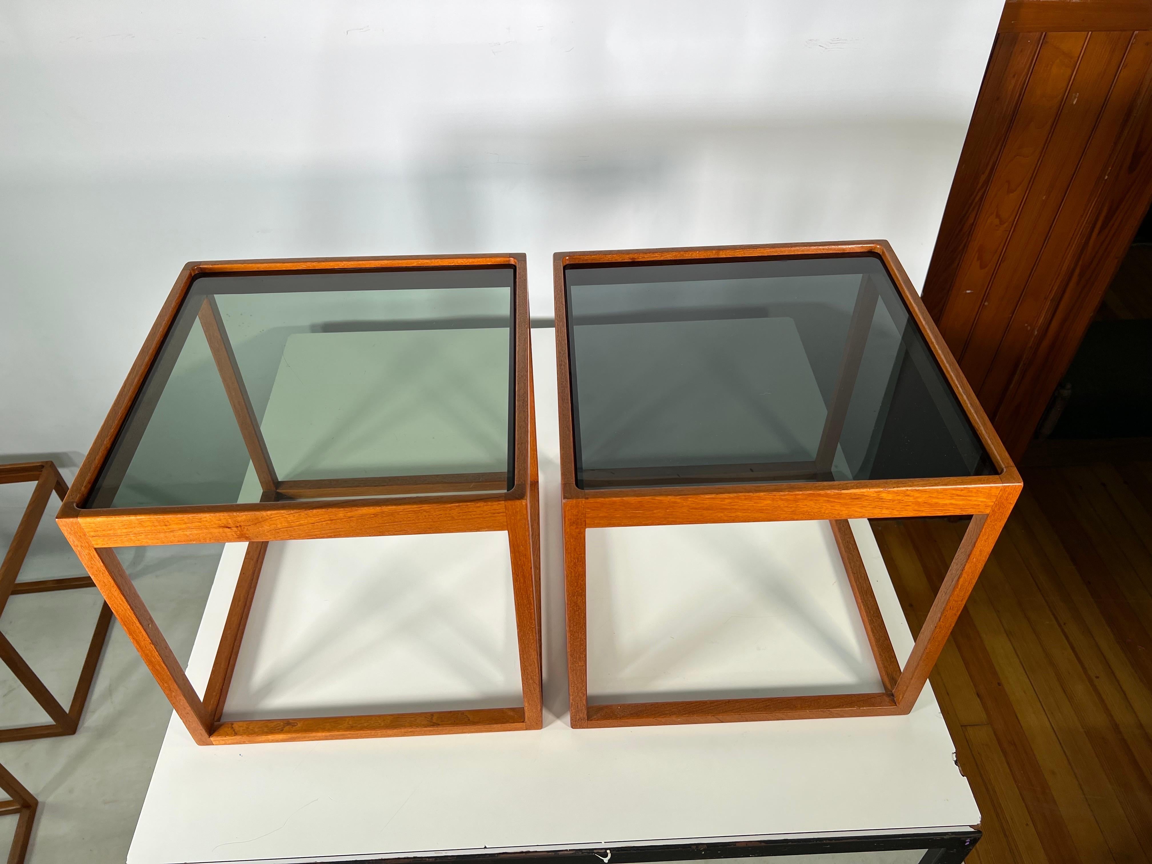 Mid century cube side tables by Kai Kristiansen - a Pair. The stands are constructed out of teak with smoke glass tops.