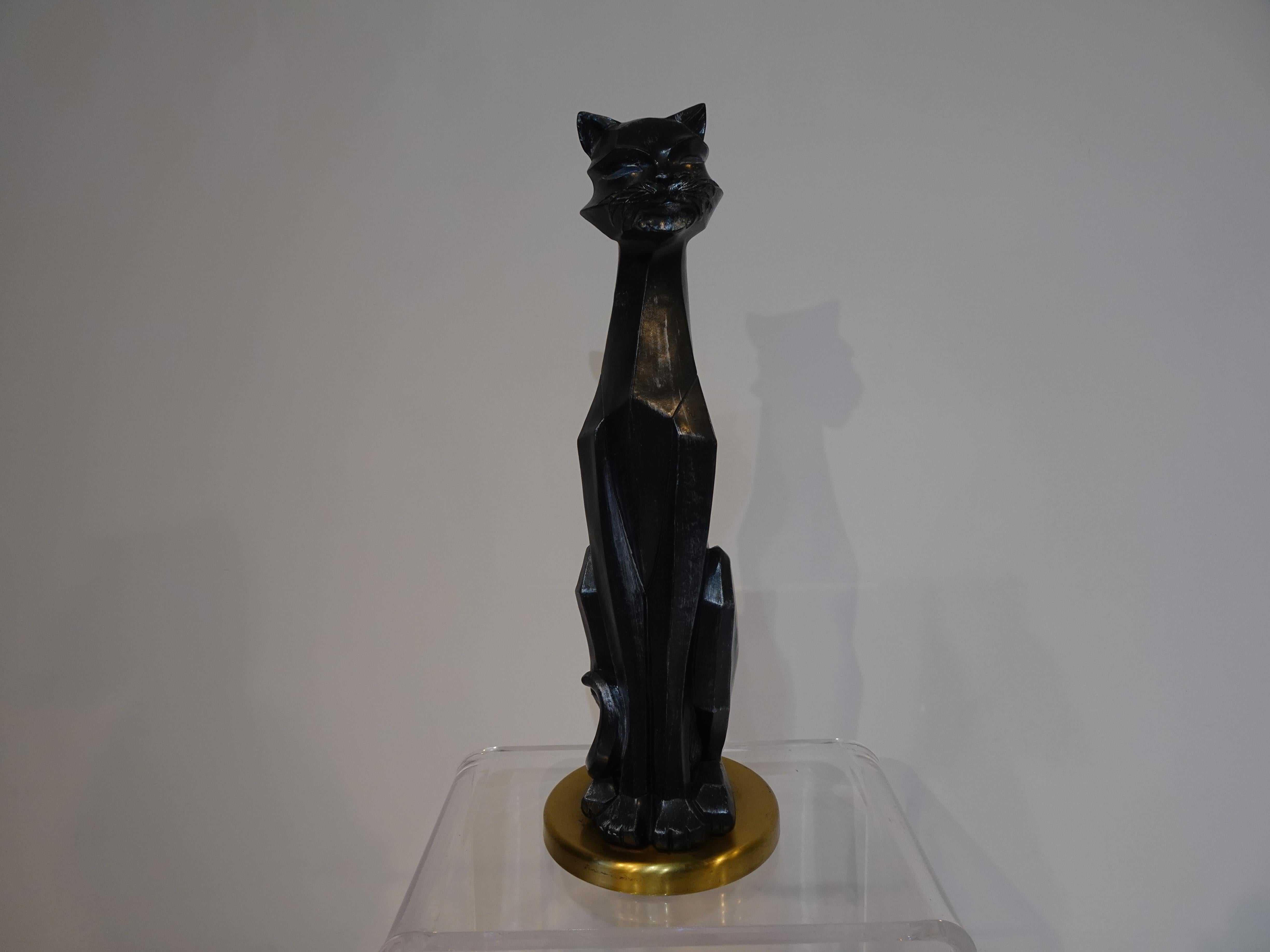 A large cat sculpture sitting on a round satin brass base, the figure is done in a cubist angler style in a mat charcoal tone cast material with brush stroked details to the body. A piece that has personality and would fit in any interior, Mid