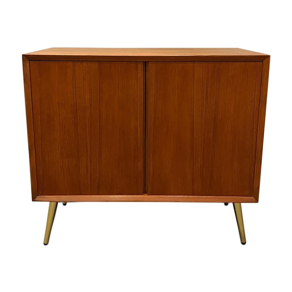 Mid-century curated teak cabinet with two open doors and brass legs. Circa 1960’s 
Dimensions: W 31.5 x D 18 x H 28” inches.