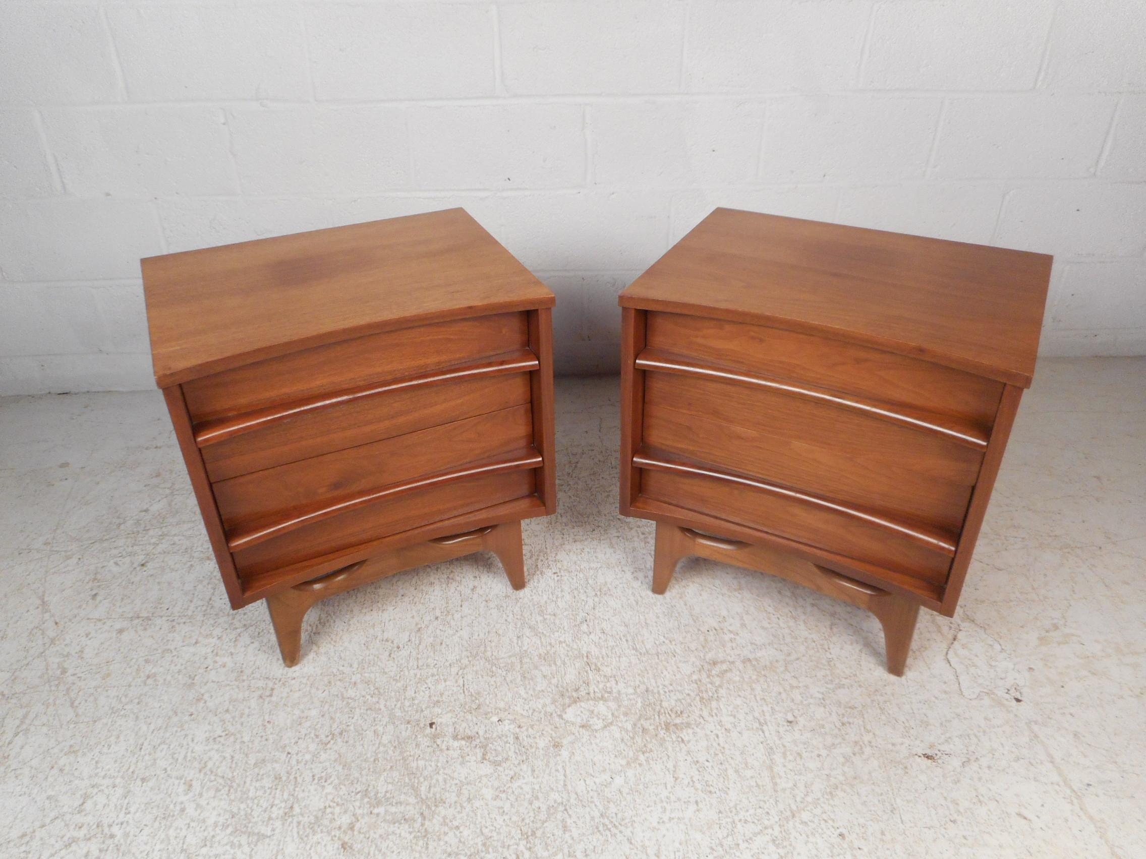 Impressive pair of midcentury nightstands. Sturdy pieces featuring a curved front end and drawers which give this pair a distinctive visual profile. Two dovetail-jointed drawers with sculpted pulls offer ample storage space with style. This pair is