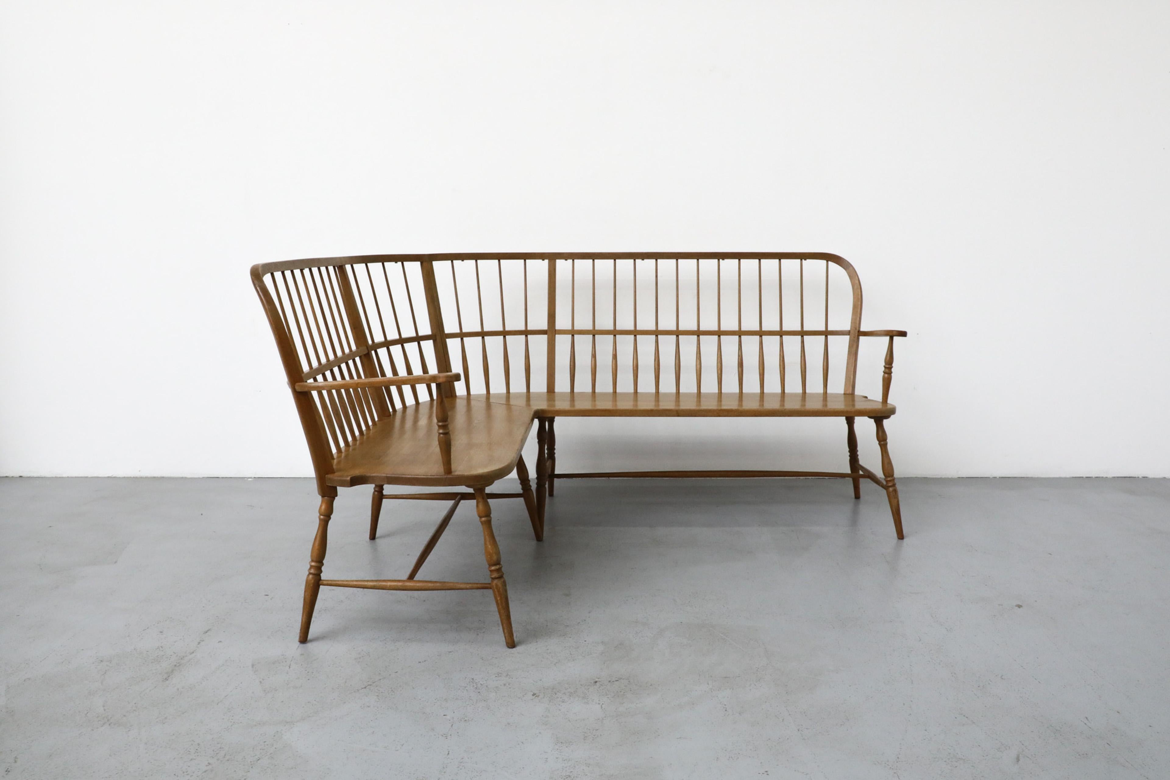 Mid-Century Oak curved spindle back corner bench inspired by Greaves & Thomas, likely manufactured in Germany. Elegant delicate hand-turned spindle backs and legs with dainty curved details. In original condition with visible patina and wear