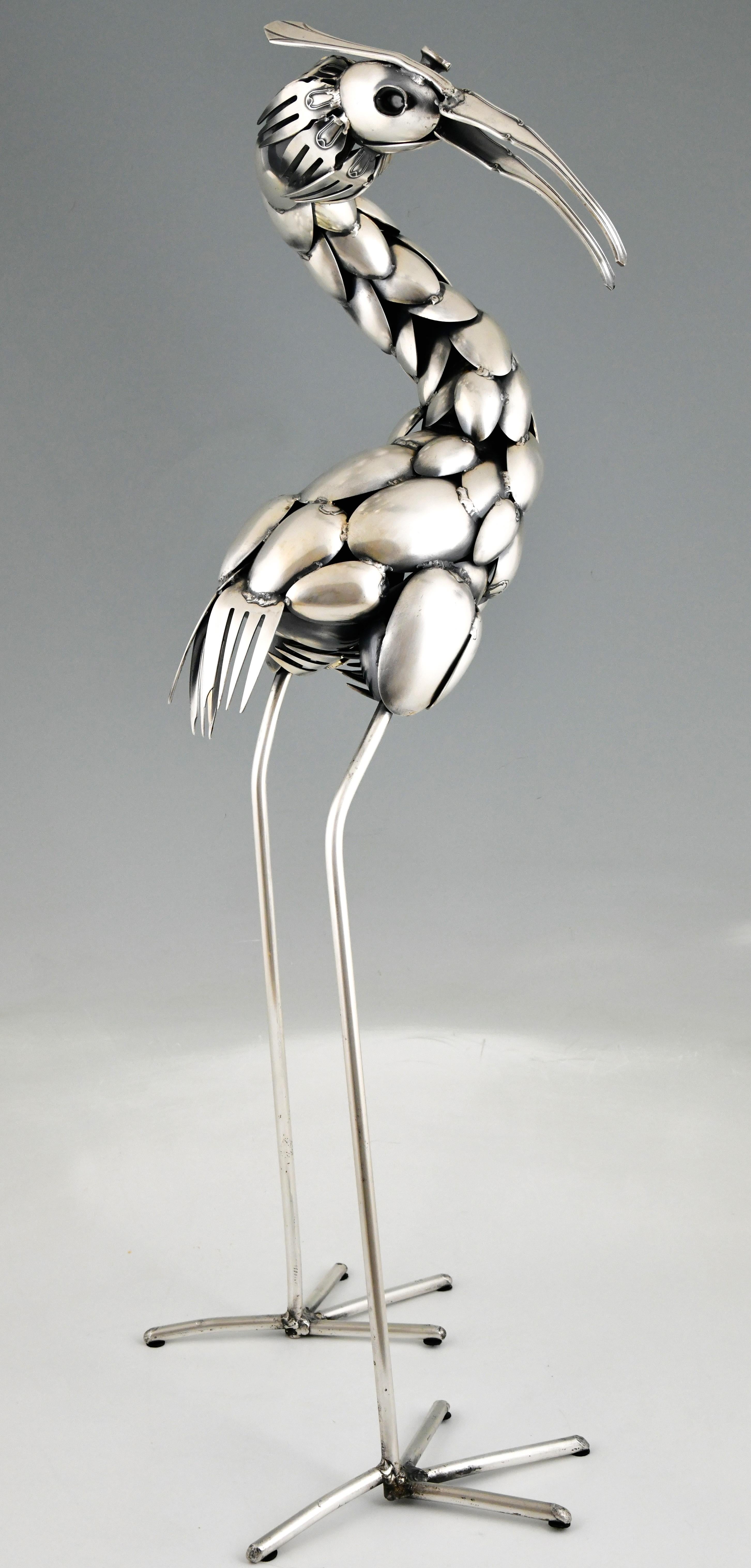 Sculpture de couverts du milieu du siècle représentant un oiseau héron par Gérard Bouvier. 
Artistics né en France en 1942. 
L'énorme oiseau est fait de fourchettes, de couteaux et de cuillères antiques. 
Métal argenté. 
Ca. 1970. Mesures : H.