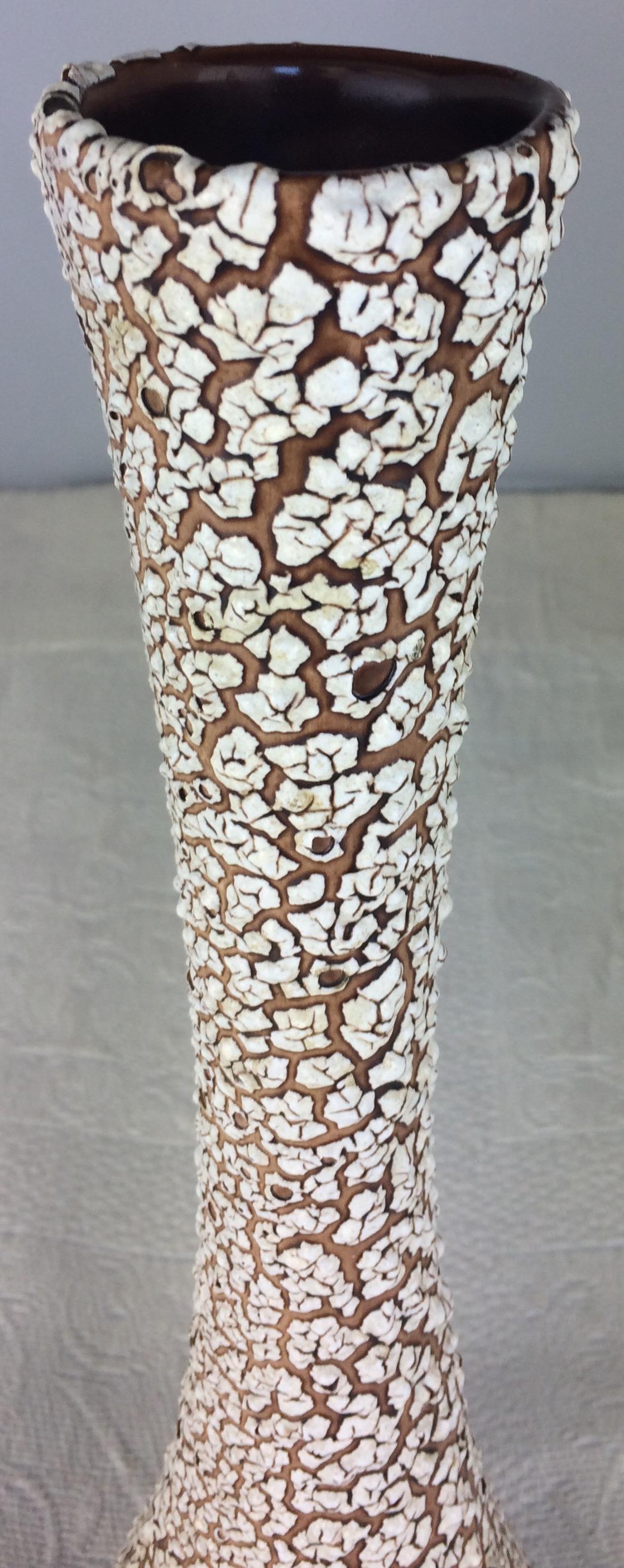 This tall dazzling piece that was produced in the 1960s is modeled after the cyclope pottery made by Charles Cart because of the volcanic dimples created during the firing of the pottery which reveal the layers below the surface. This item is