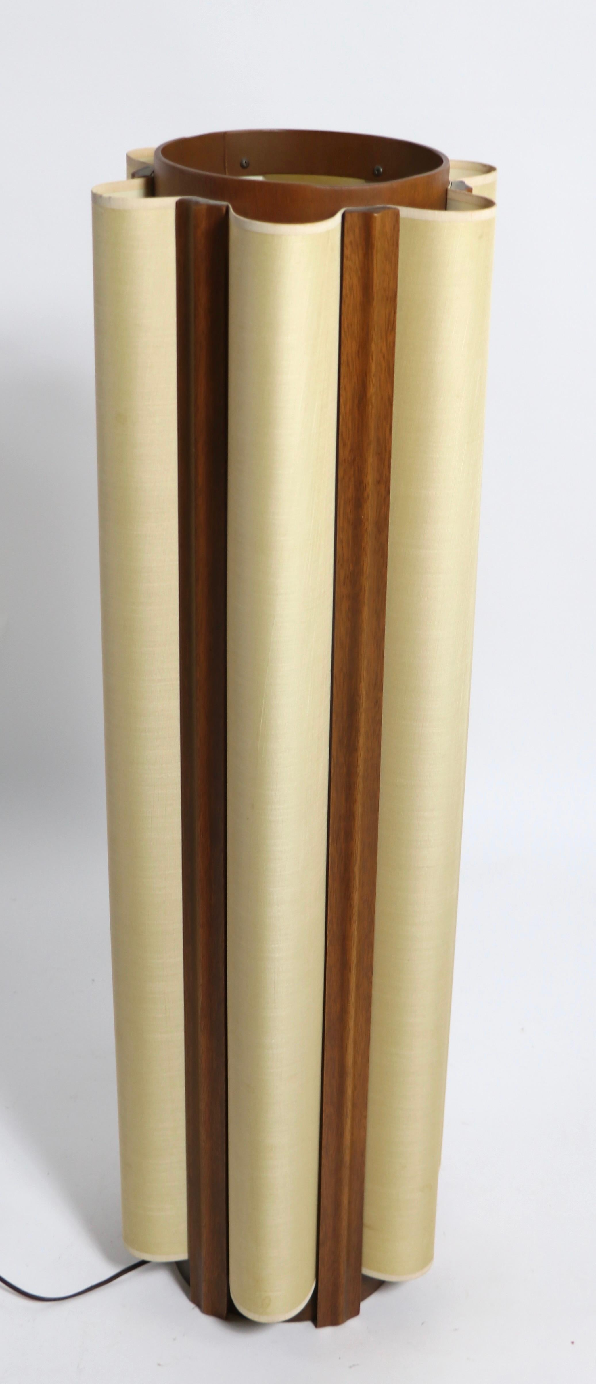 Extraordinary cylinder lamp having an undulating paper shade which surrounds the interior. The lamp has a wood frame, probably walnut, with vertical wood trim elements. The interior has two sockets, an upper and a lower, which can be operated