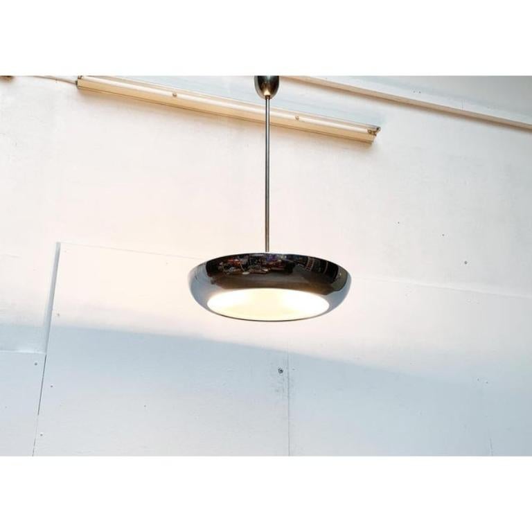 Imponente lampada a sospensione a stelo di Napako su disegno di Josef Hurray.

Un design elegante di speciale matericità. Un'interazione tra vetro e alluminio riflettente. Lo schermo è costituito da un guscio piatto di alluminio. Il guscio è montato