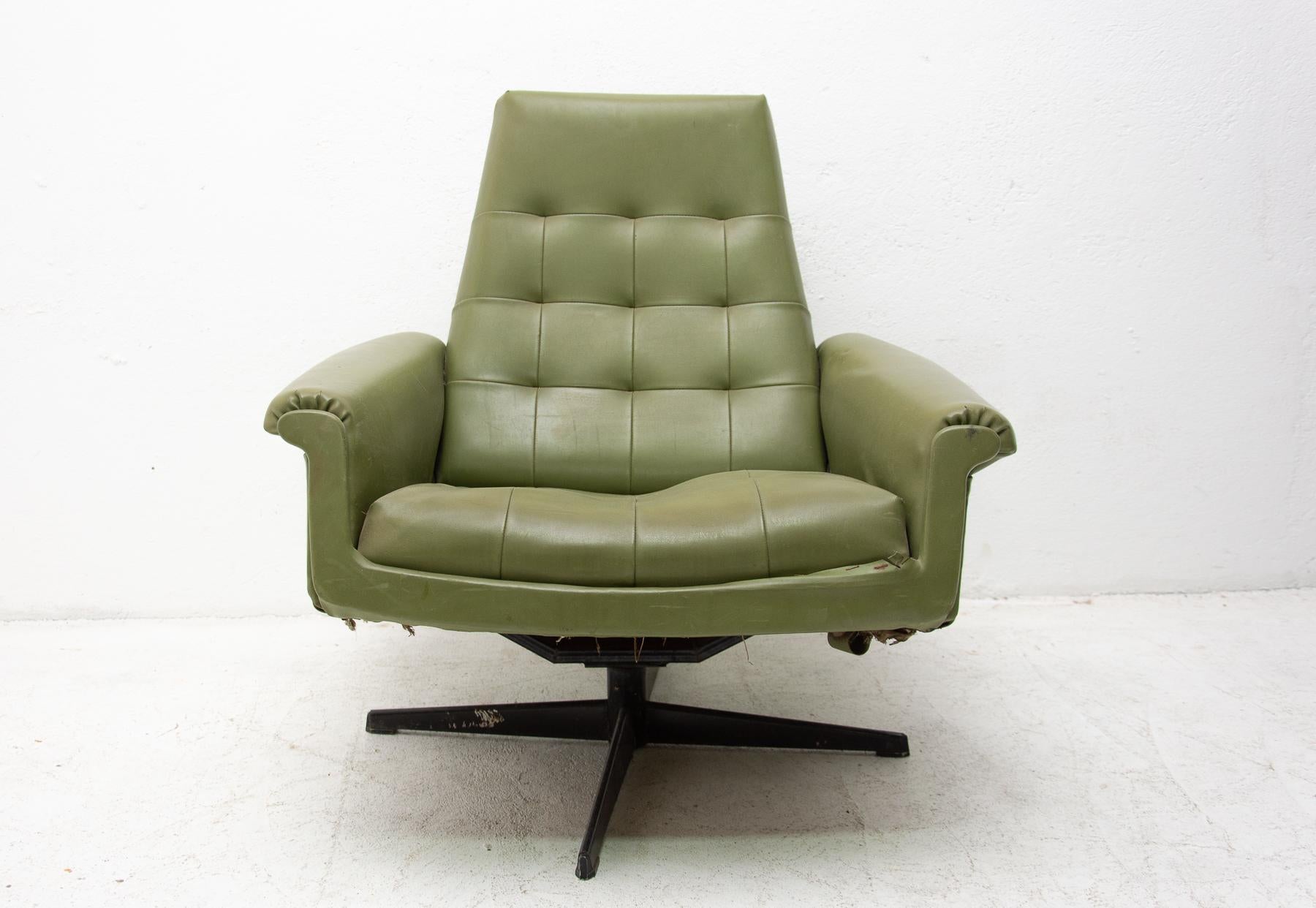 This armchair was made in the former Czechoslovakia in the 1970 as a part of living room set consists of one sofa, pair of swivel armchairs and stool. The chair is upholstered with green leatherette. The legs are made from iron. All in original