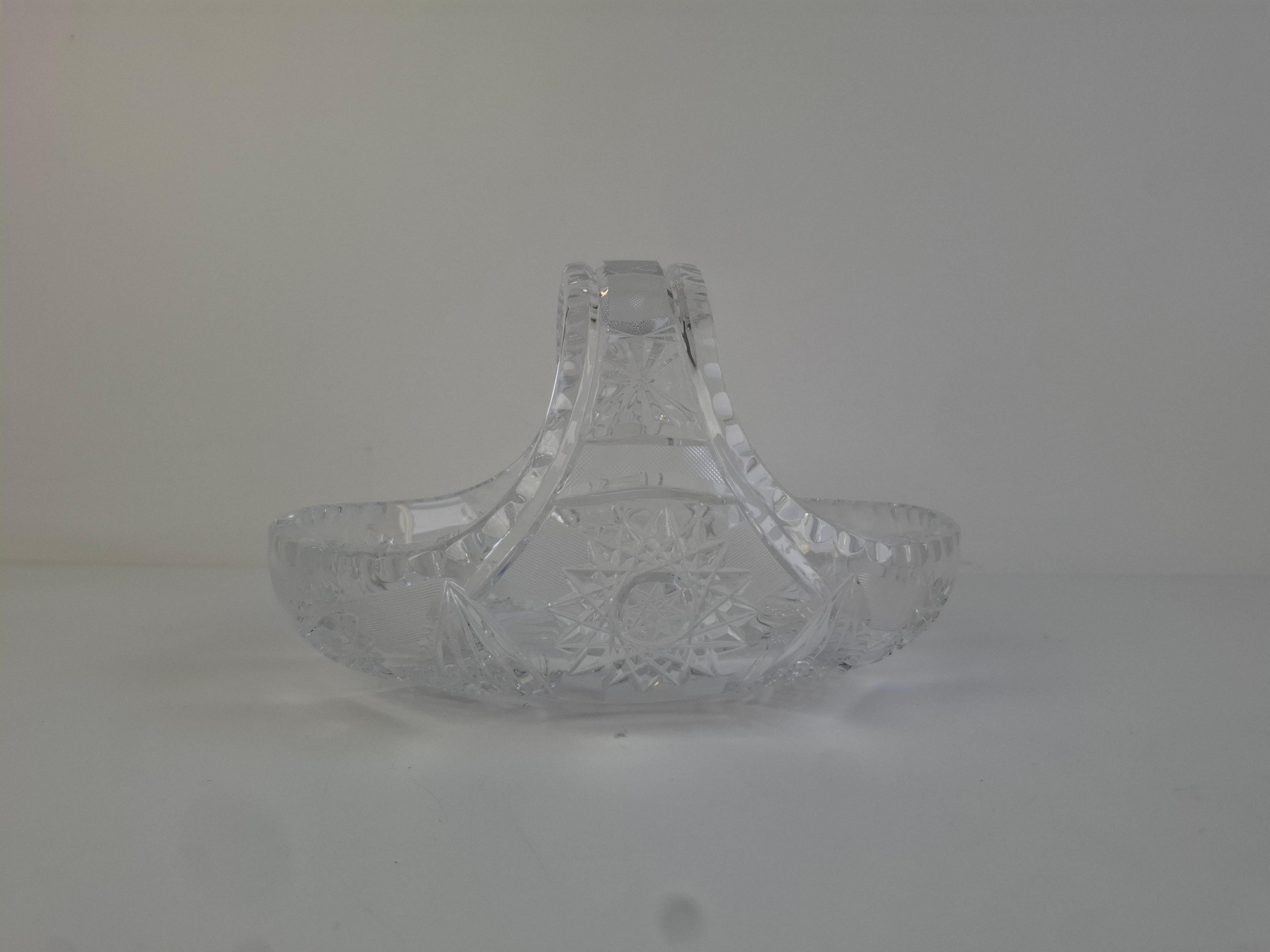 A mid-century cut crystal basket produced in Czechoslovakia, featuring deeply engraved starburst motifs and a sculpted arched handle characteristic of Bohemian glassmaking. The high-clarity crystal and precision-cut facets deliver notable brilliance