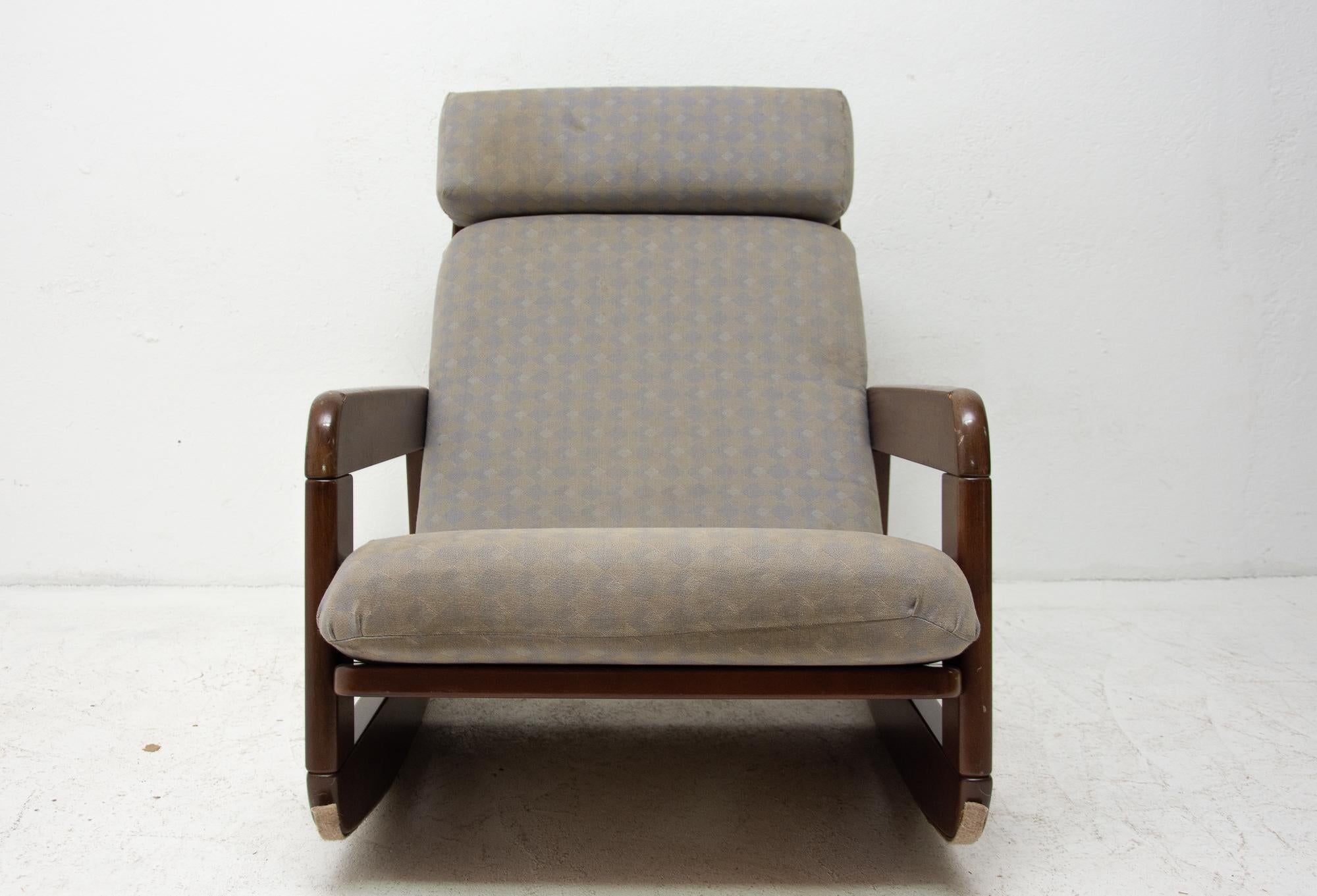 Cette chaise à bascule en bois courbé rembourrée a été fabriquée en Tchécoslovaquie dans les années 1960. Le cadre est probablement en bois de hêtre teinté et présente de légers signes d'utilisation.
La tapisserie est d'origine, usée sur le siège,