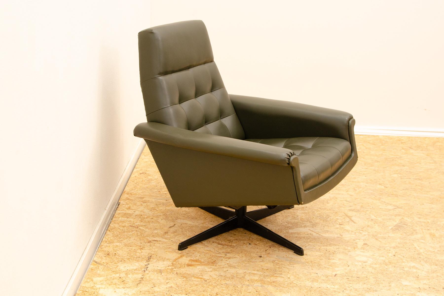 This swivel armchair was made by UP Závody company as a part of living room set consists of one sofa, pair of swivel armchairs and stool. It was made in the former Czechoslovakia in the 1970´. The chair is upholstered with dark green leatherette.