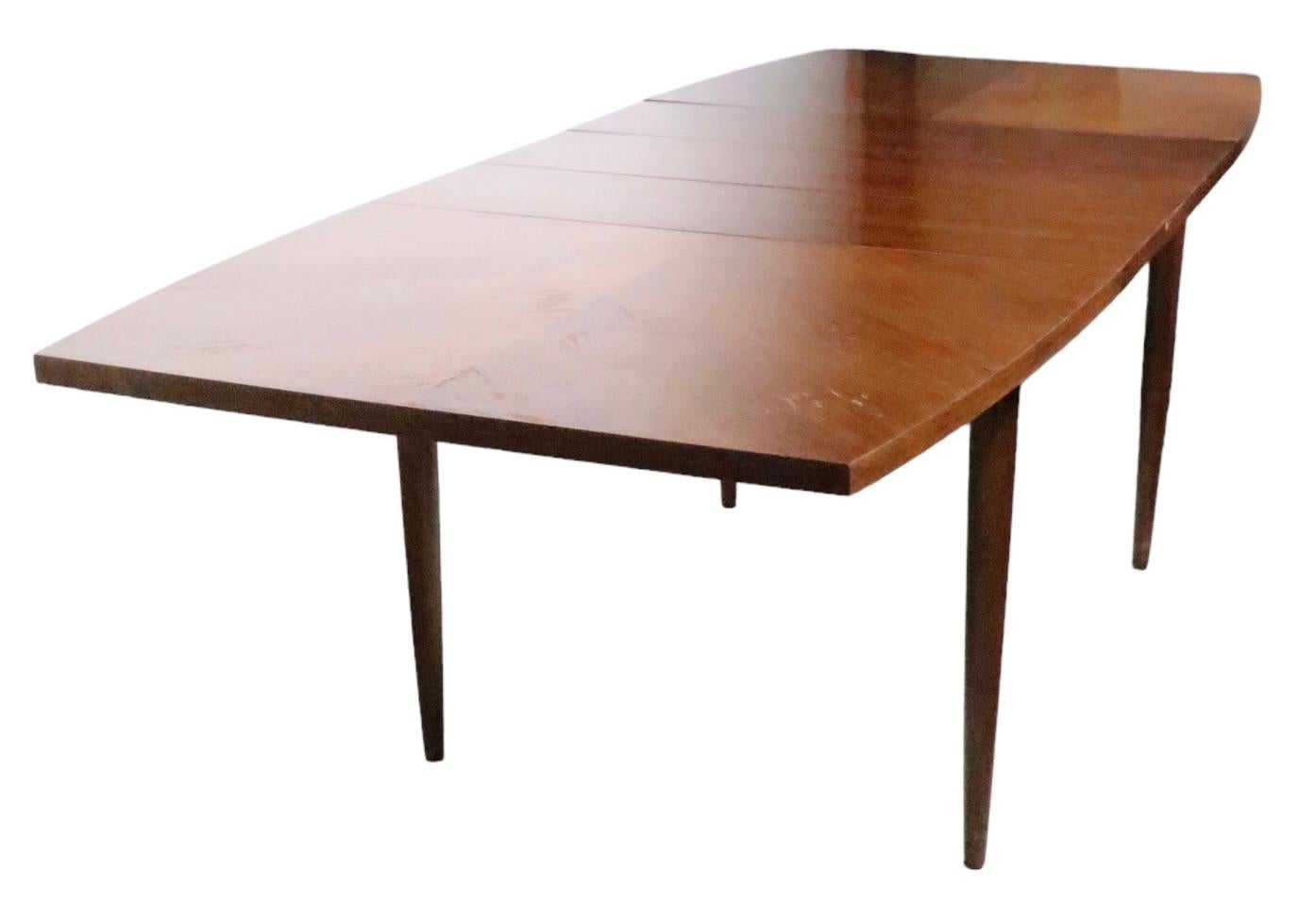 Classic Mid-Century Modern dining table designed by Merton Gershun for American of Martinsville, as part of their Classic Dania line, circa 1950s. The table features a boat shaped top, with book matched veneer, and comes with three large ( 12 inch )