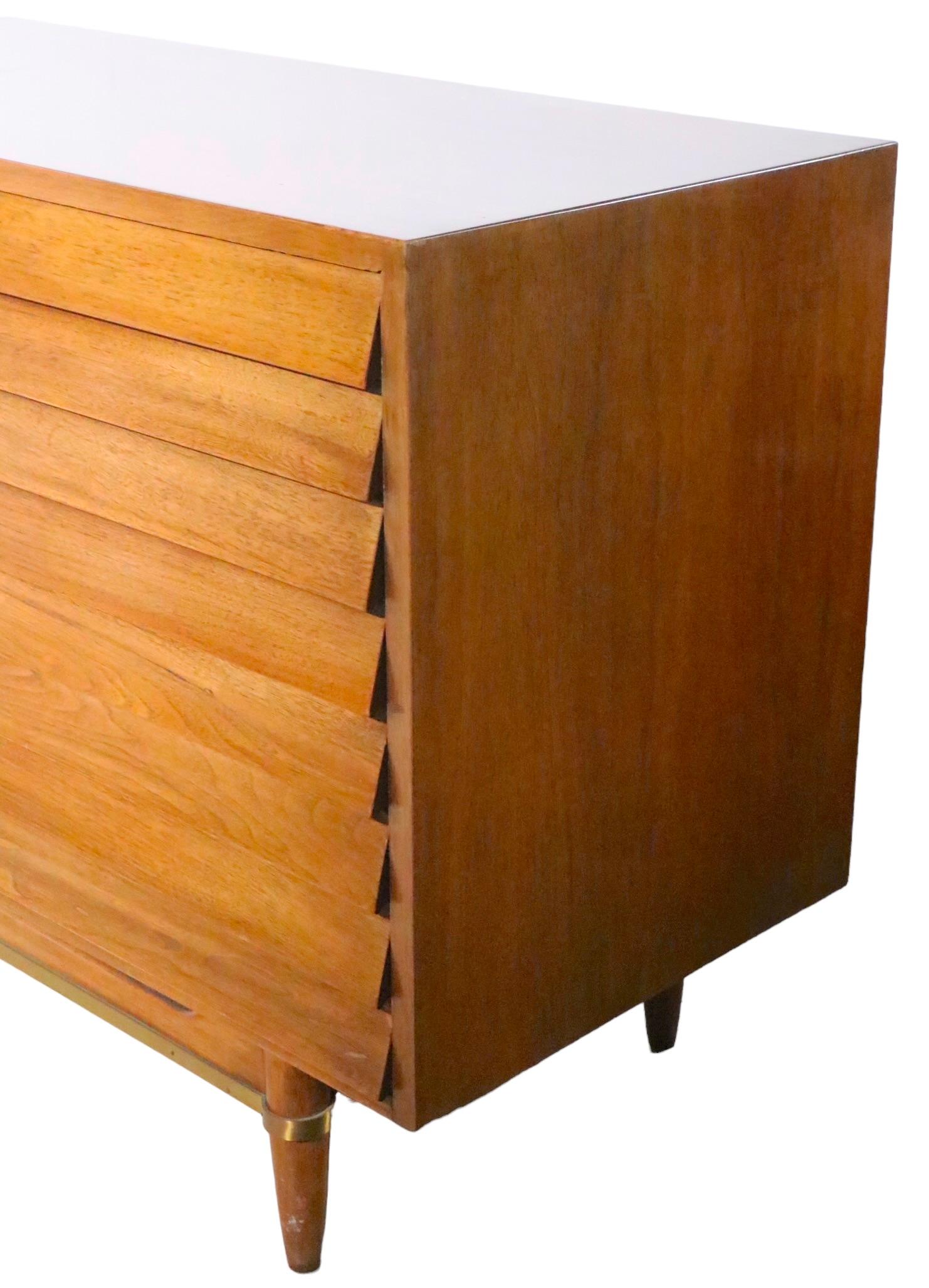 Classic midcentury dresser designed by Merton Gershun for American of Martinsville, as part of the iconic Dania series, circa 1950s. The chest features two banks of three louvered front drawers, which flank two doors that open to reveal three
