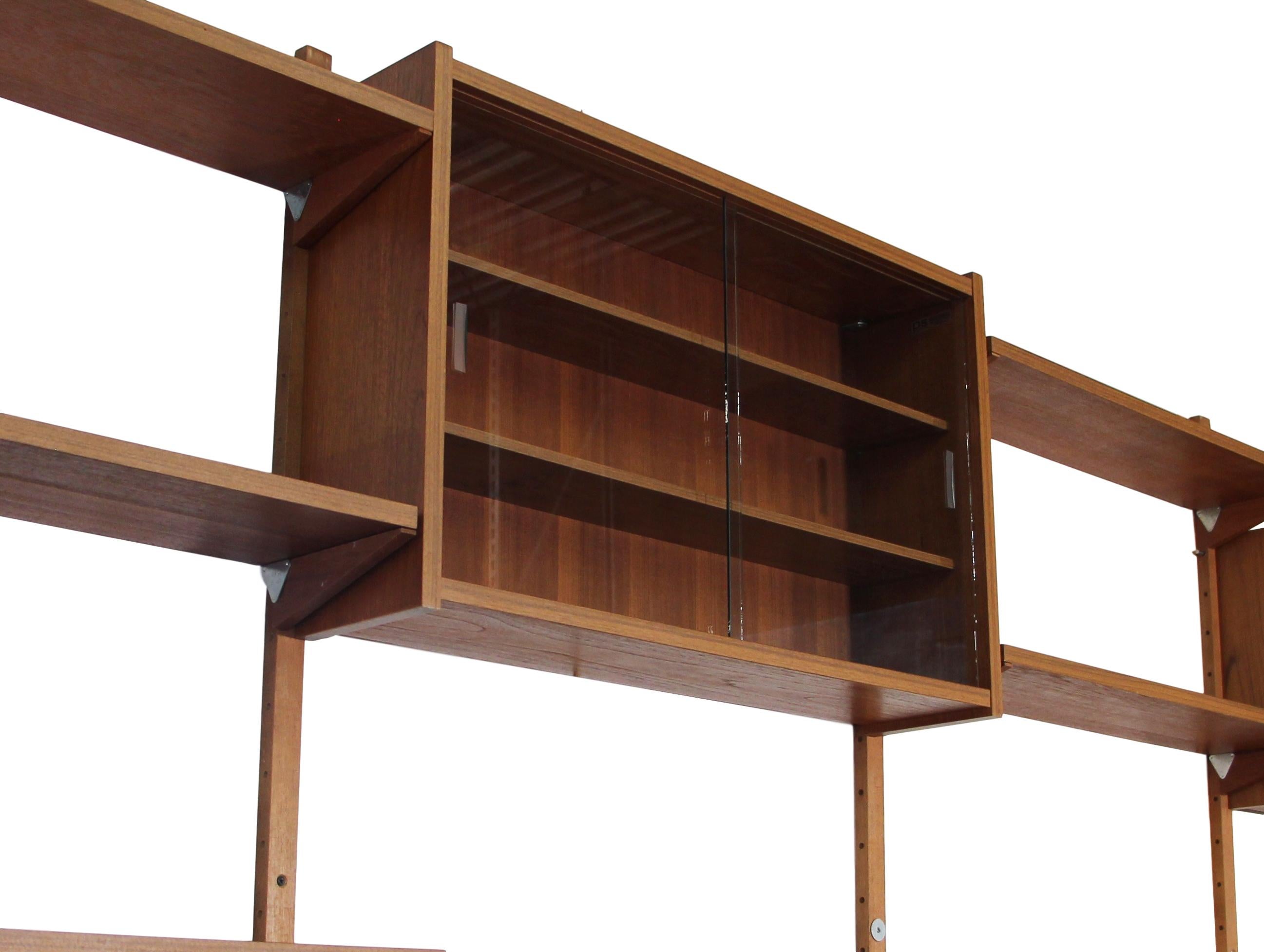 This is a stunning midcentury 7 bay teak shelving unit by PS System. Made in Denmark. Similar to Cadovius units.

It is a modular unit. You can arrange it in many different ways.

It consists of 2 upper glass sliding door cabinet, 1 open slotted