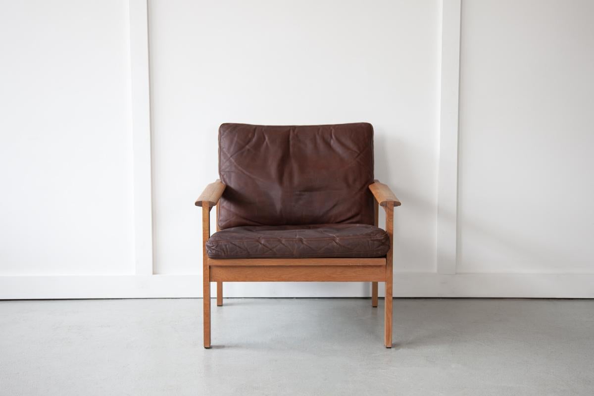 The handsome 'Capella' armchair by Illum Wikkelsø for Niels Eilersen, with an elegant solid oak frame that displays a relaxed stance. The two loose box cushions are in original brown leather which is soft, well lived-in and in good vintage