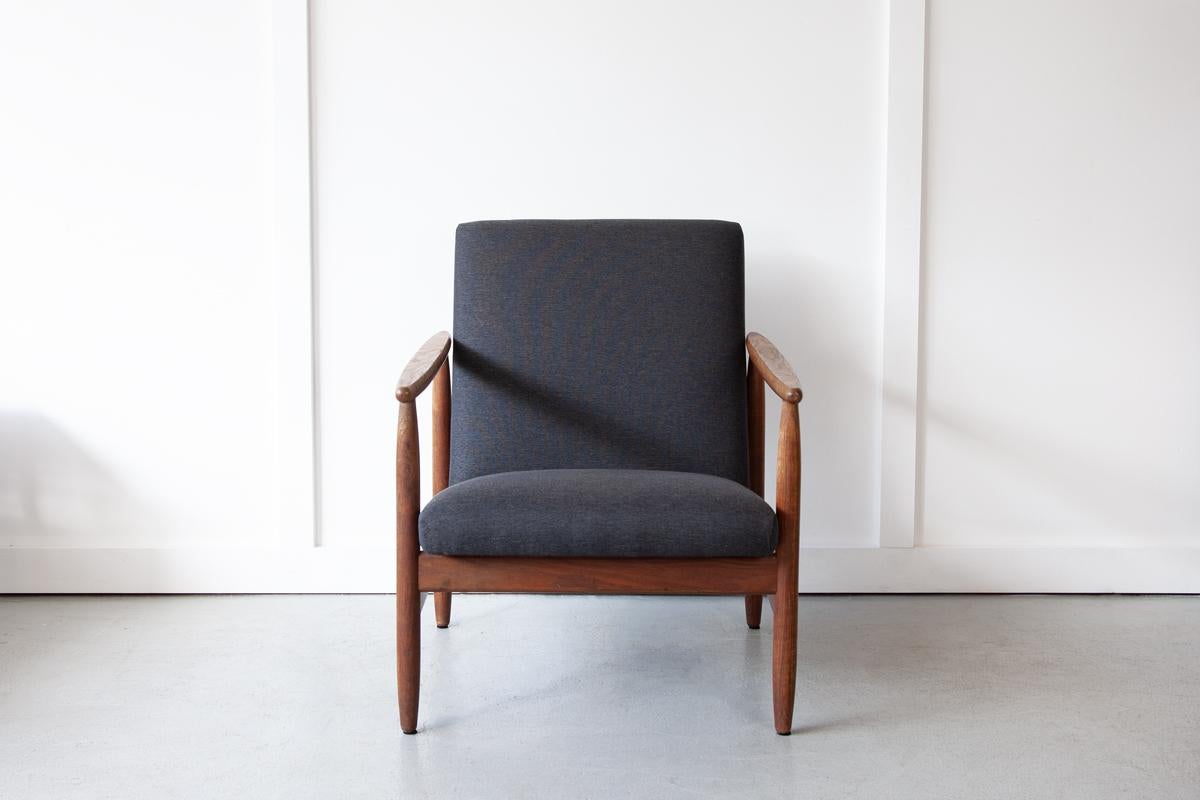 Un beau fauteuil danois avec de longs et élégants accoudoirs qui se rétrécissent aux deux extrémités, et une assise profonde et confortable. L'endroit idéal pour passer un après-midi à lire. Le cadre en chêne présente de jolis détails de grain et