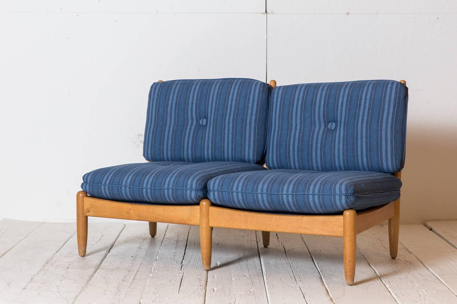 Midcentury Danish armless settee with six legs, cushions newly upholstered in blue striped fabric with button details.