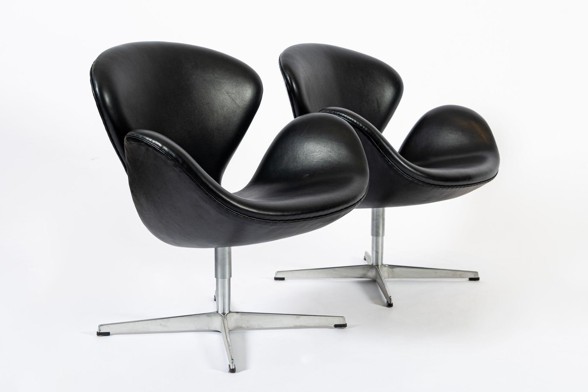 This pair of mid century Danish modern black leather Model 3320 Swan chairs by Arne Jacobsen for Fritz Hansen were made in Denmark in 2006. Arne Jacobsen was a design visionary and creator of the Egg, Swan, Series 7, and Drop chairs, among other