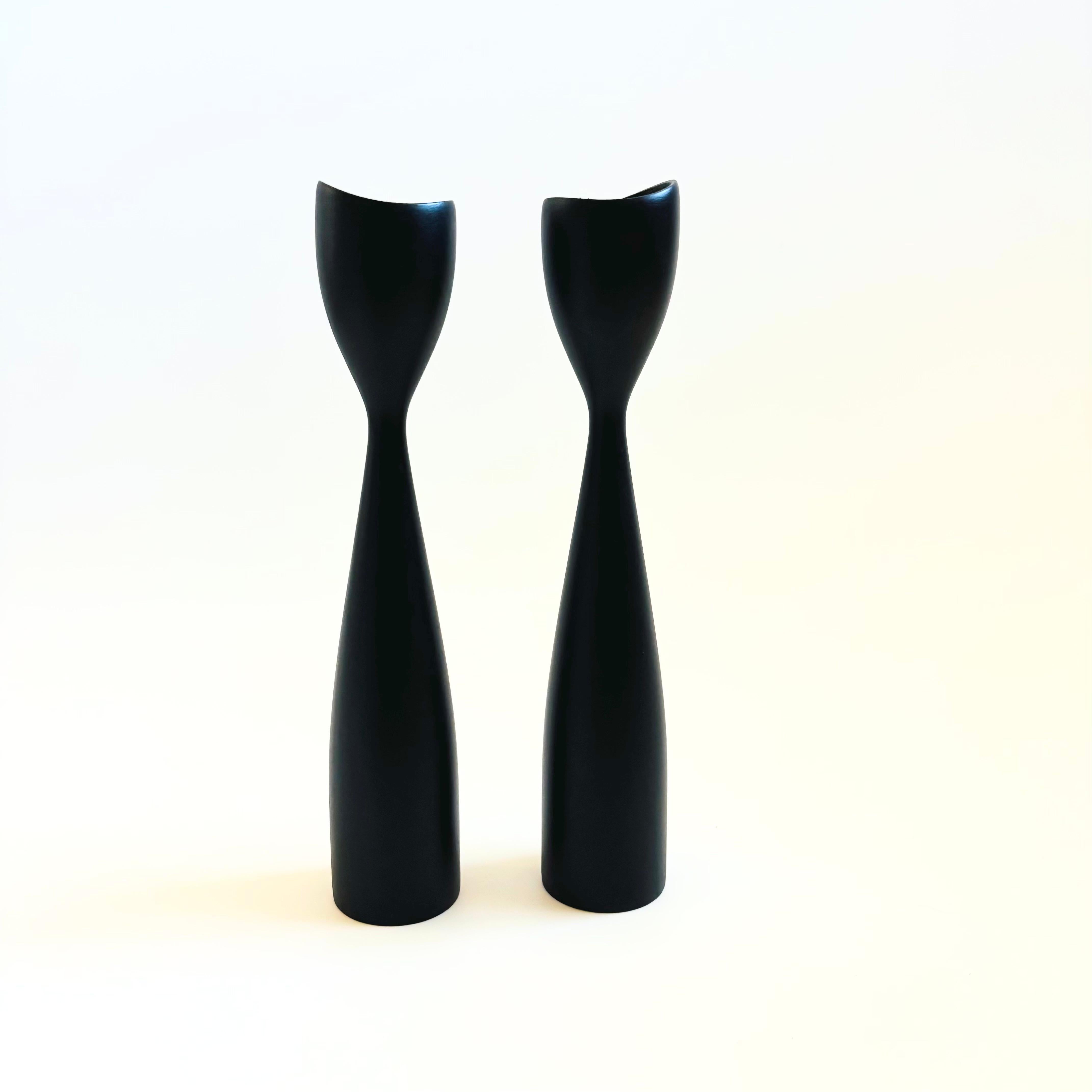 A pair of mid century Danish turned wood candle holders. Matte black painted finish. Made to hold standard taper candles. Made in Denmark, one candle holder has the original sticker attached.


