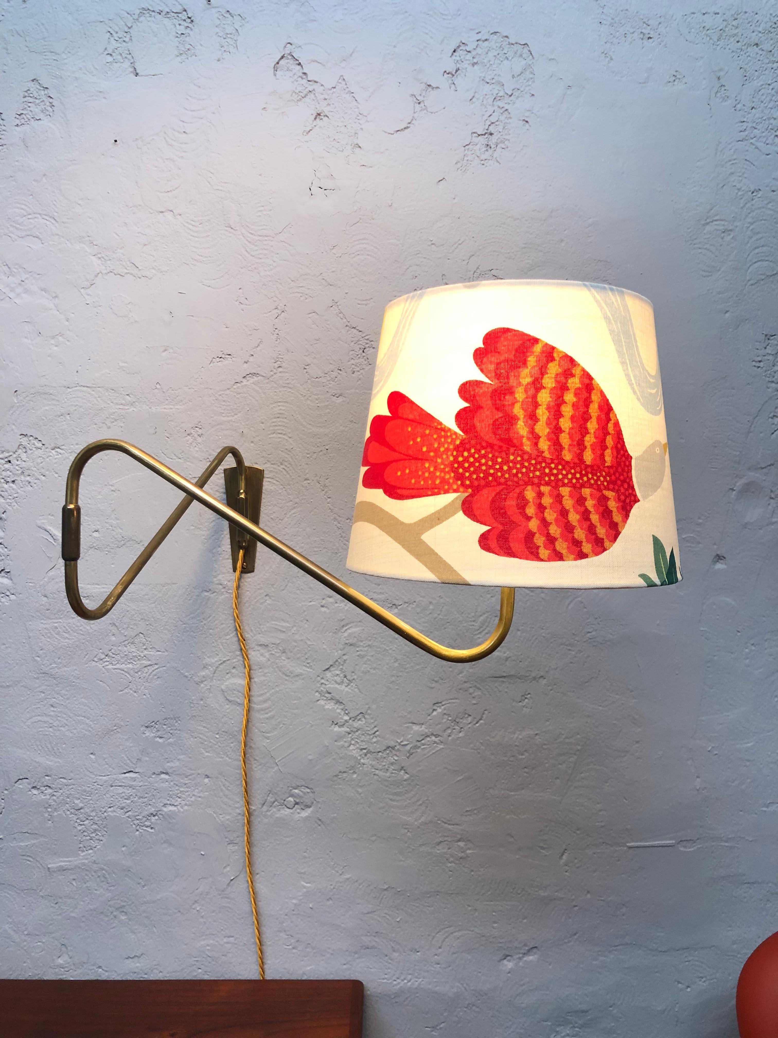 A Danish midcentury brass wall lamp by Fog And Morup. 
Lovely patina to the brass. 
Fitted with a new lampshade that has been refurbished with beautiful vintage fabric entitled “Birdland” by Ann-Christin Sigrid. 
Also fitted with a new lampshade