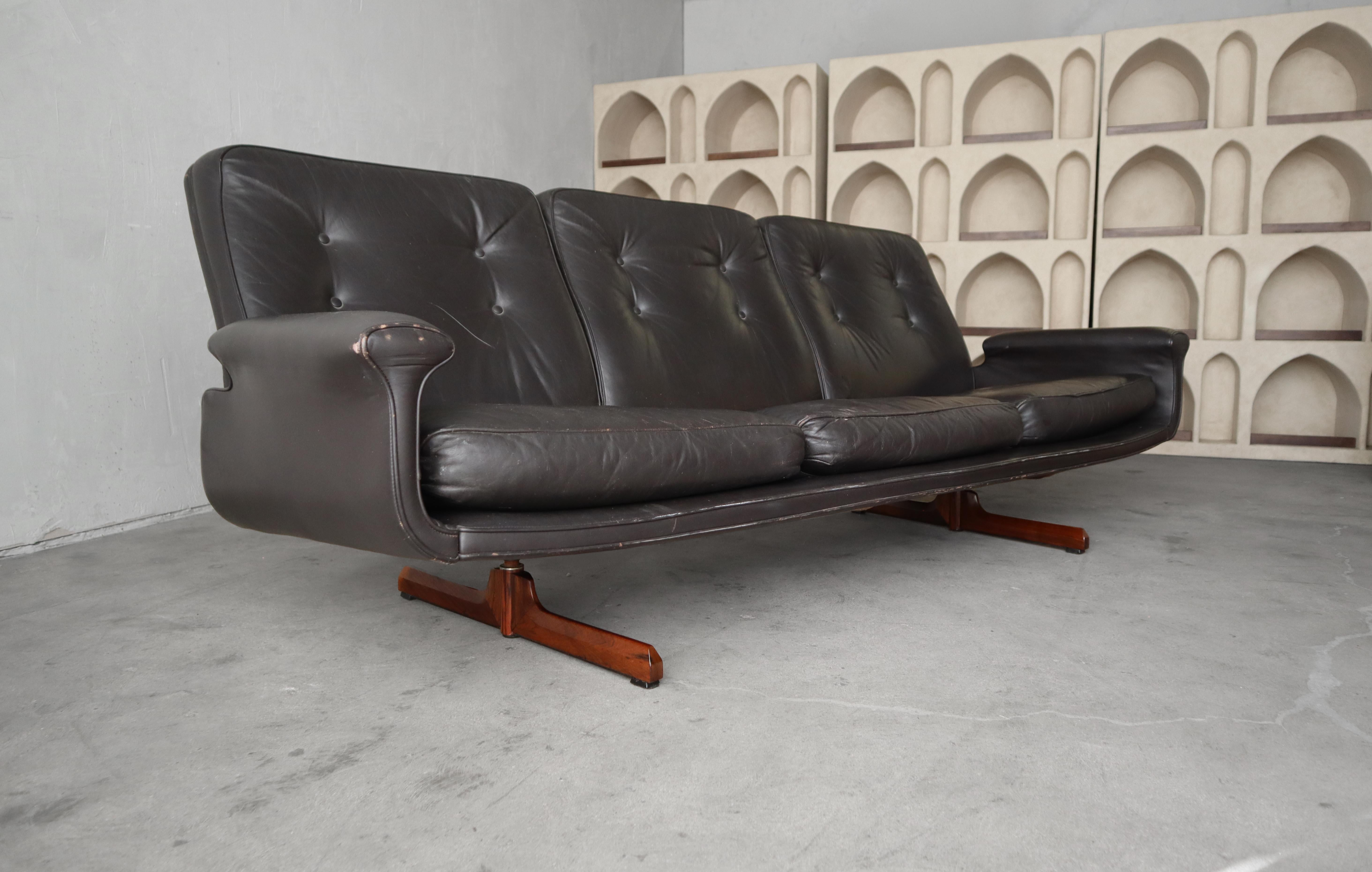 Simple Mid Century Danish Sofa with an executive sort of feel.  Manufactured by Soda Gavano

Sofa is dark chocolate leather with a rosewood base.

Sofa is well loved.  Leather shows some wear from age and use but it is free of any actual damage, see
