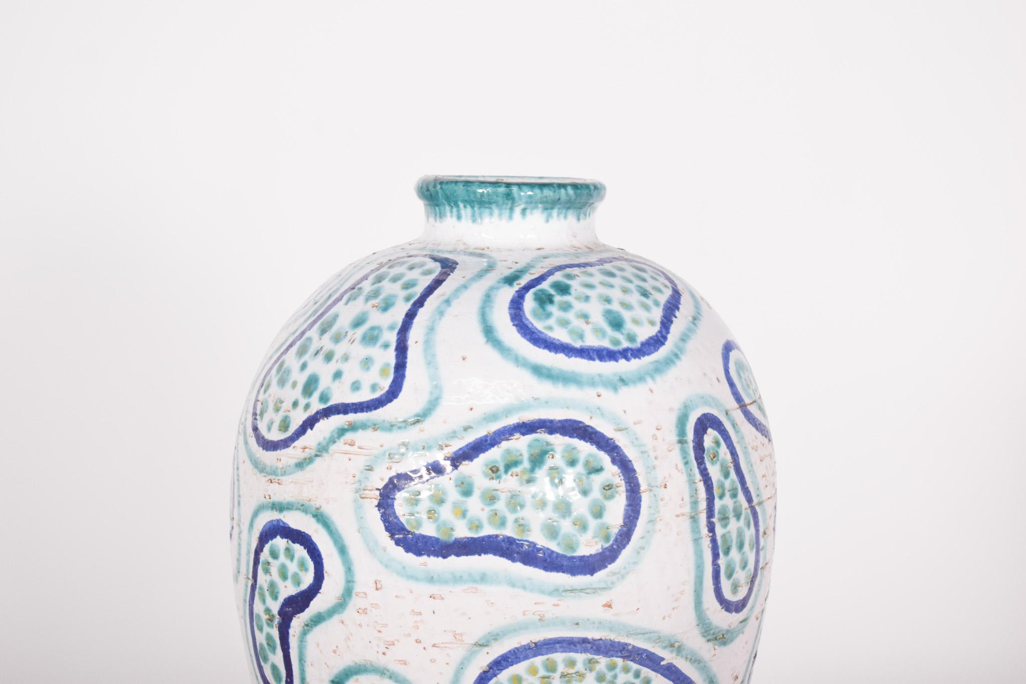 Vaso in ceramica degli anni '40.  Con un motivo astratto dipinto a mano, ha una base arrotondata che si assottiglia leggermente verso l'alto e termina con una piccola apertura circolare. La superficie è prevalentemente bianca, con disegni nei toni