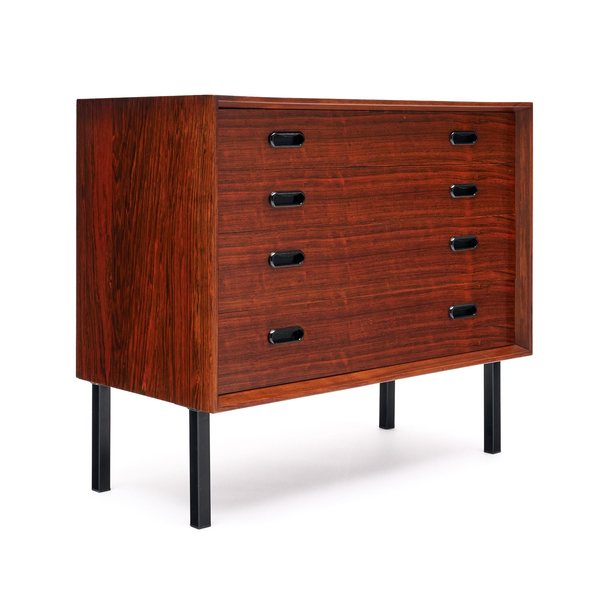 Pequeña cómoda danesa de mediados de siglo fabricada en madera maciza, principalmente palisandro. Esta pieza tiene cuatro patas de metal lacadas en negro. Los cuatro cajones de cola de milano presentan tiradores de madera ebonizada. Este arcón está