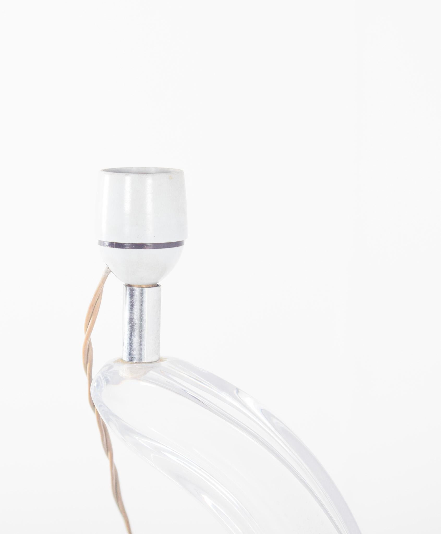 Lampe en verre transparent. Avec un design moderne et sculptural qui évoque la fluidité d'une flamme ou le mouvement d'une vague. La structure du corps de l'abat-jour est en verre moulé, travaillé avec beaucoup de légèreté et d'harmonie, reposant