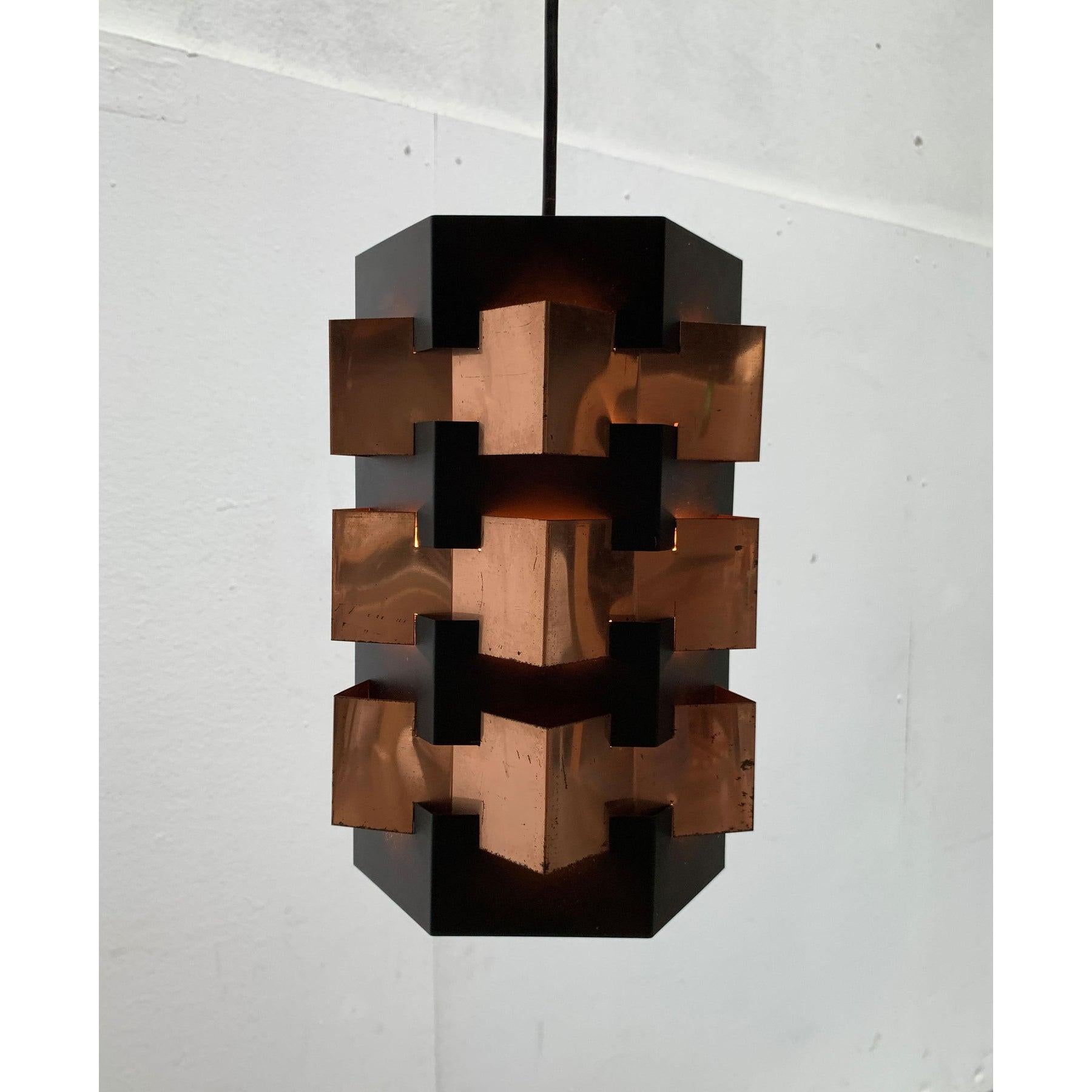 Rara lampada a sospensione a lamelle di Lyfa. Probabilmente un disegno di Luigi Weisdorf.

La lampada convince per la sua chiara geometria. La forma di base è un corpo nero esagonale. Tre nastri di rame sono intrecciati nell'elemento centrale. La