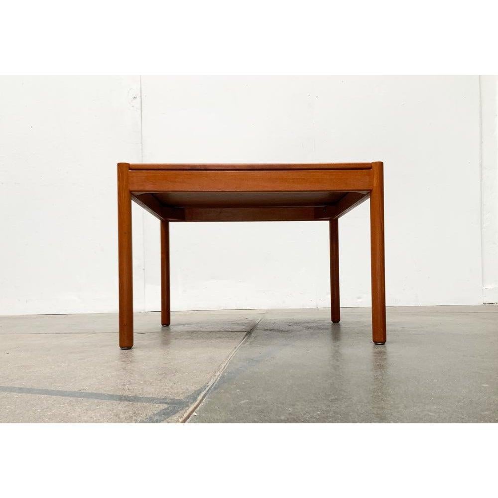 Minimalist teak coffee table from the Danish manufacturer Magnus Olesesen from the 1960s.

A very straight design. The legs are simple cylinders that protrude beyond the surface of the table. They are connected to a frame with straight rams. The