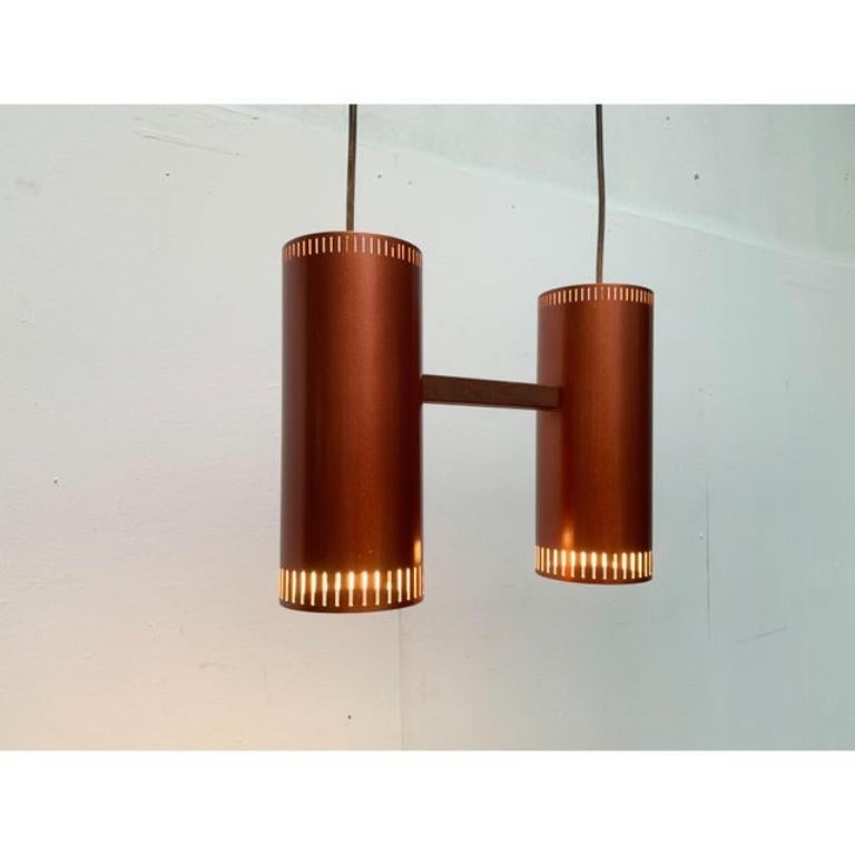 Seltene Zylinder-Doppelpendelleuchte des dänischen Herstellers Fog & Mørup nach einem Entwurf von Jo Hammerborg aus den 60er Jahren.

Der Leuchtenkörper besteht aus zwei einfachen Zylindern aus Aluminium, die außen kupferfarben lackiert sind. Der
