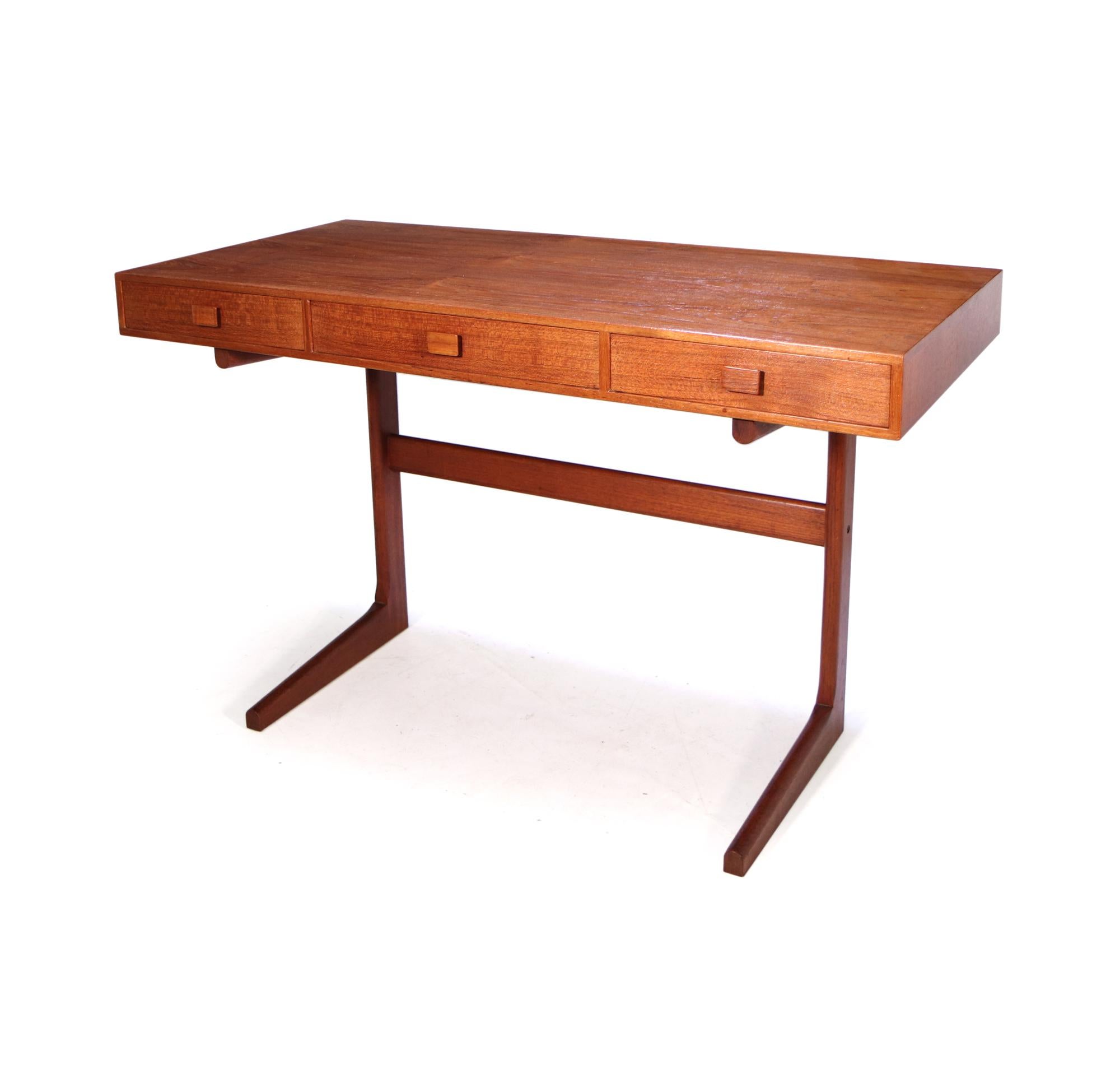 A mid century desk designed and produced in Denmark in the 1960’s by Georg Petersons, minimal sleek design with good colour and patination to the desk, three drawers with original square teak handles the teak leg frame provides a spacious kneehole.