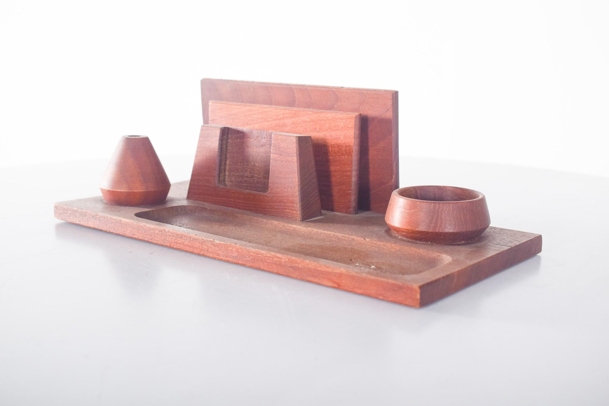 Desk organizer, in teak. The rectangular base integrates compartments with different depths and shapes, a hollowed-out tray for small objects, two circular containers, one of which is ideal for paper clips, erasers, etc., a pen or pencil holder, and