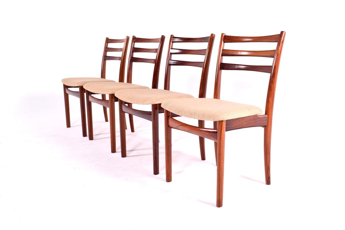 Cet ensemble élégant de quatre chaises de salle à manger a une structure en teck avec un dossier en échelle et un siège rembourré. Ce merveilleux ensemble danois de chaises de salle à manger assure un confort maximal. Les chaises sont