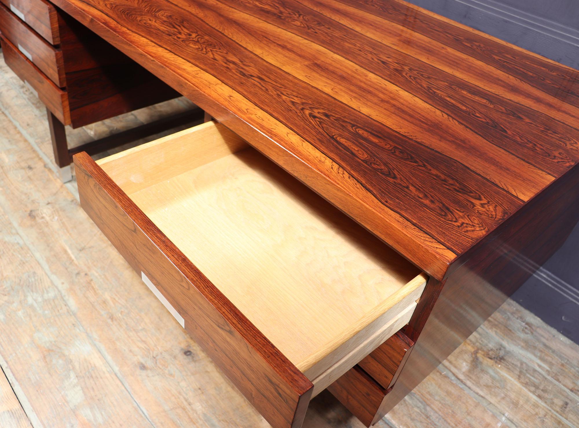 Midcentury desk EP401
A freestanding desk manufactured by Eigil Pedersen in Denmark in the 1960s is made from rosewood and has a large rectangular top with 6 drawers standing upon formed legs with aluminium tipped feet and drawer handles. The