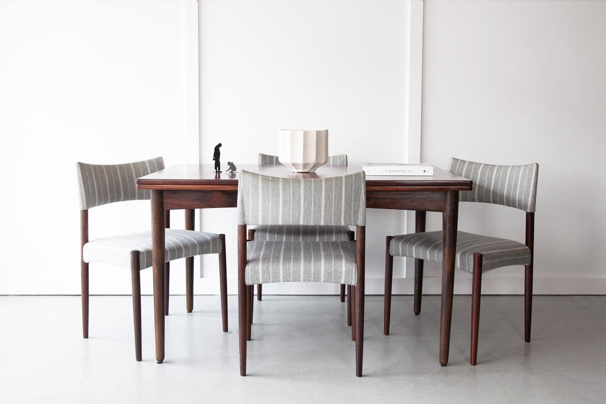 An elegant rectangular rosewood dining table with stylish tapering legs and beautiful grain detailing across the table top. Two extending leaves pull out from beneath the table top at each end to allow for larger gatherings. 