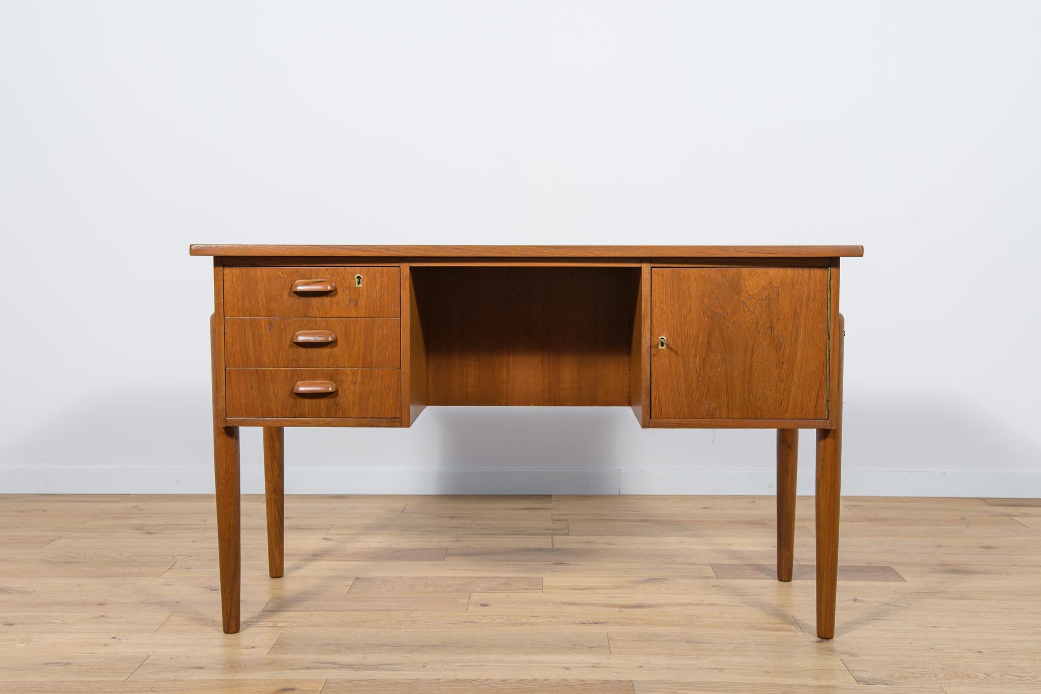 Dieser Schreibtisch wurde in den 1960er Jahren in Dänemark hergestellt. Er war aus Teakholz gefertigt und hatte konturierte Griffe. Es besteht aus zwei Modulen, links mit drei Schubladen, rechts mit einem abschließbaren Schrank. Im hinteren Teil