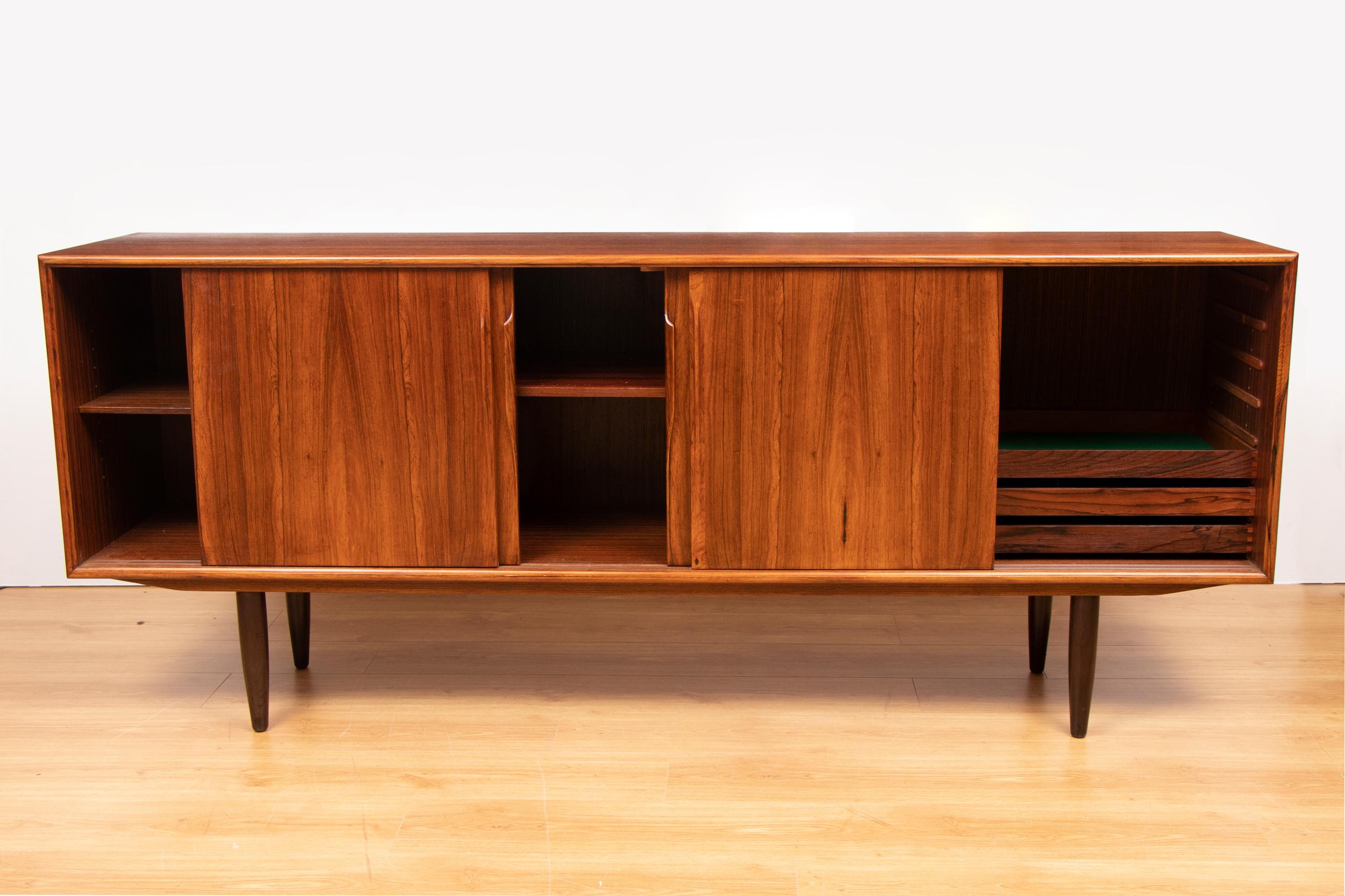 Danish rosewood sideboard with four sliding doors each having sculptural handles. Interior fitted with shelves and drawers.