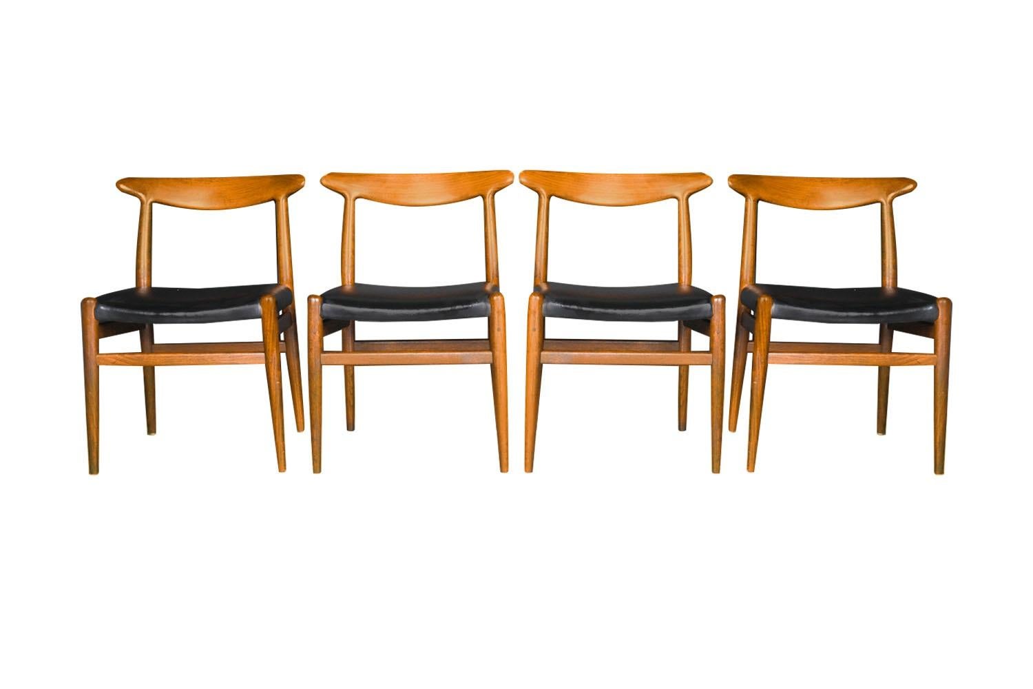 An exceptional set of four original 'W2' model chairs, designed by Hans J. Wegner, Denmark, circa 1960's. The teak frames feature modern styling with a distinct beautiful design, sculpturally carved backrests and rich, warm teak frames. Each seat