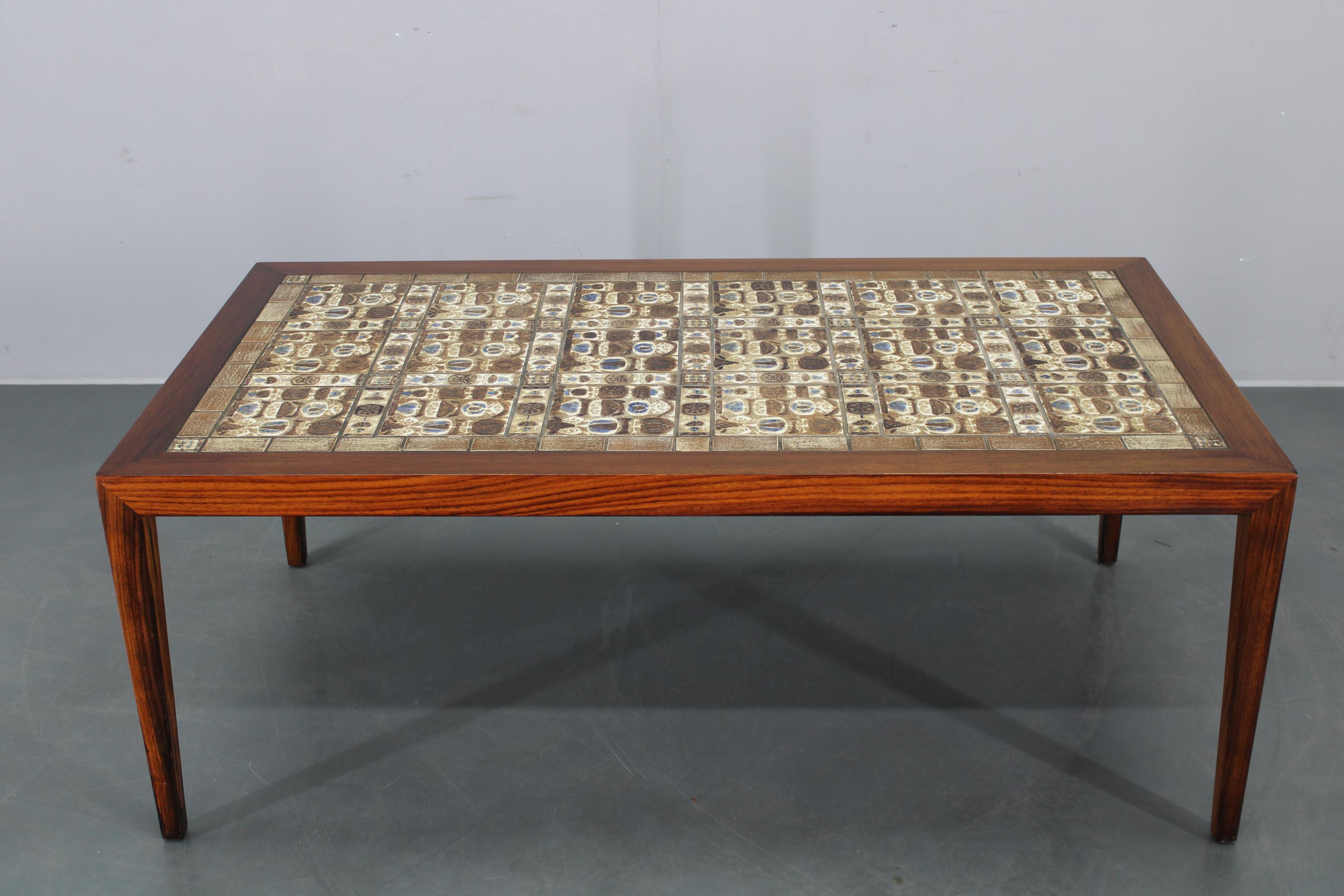Vintage Danish coffee table made by Haslev Mobelsnedkeri, Denmark, circa 1960s. This expertly refurbished piece features a wood veneer frame and an intricately tiled top with Royal Copenhagen ceramic tiles, distinguished by their heat-resistant
