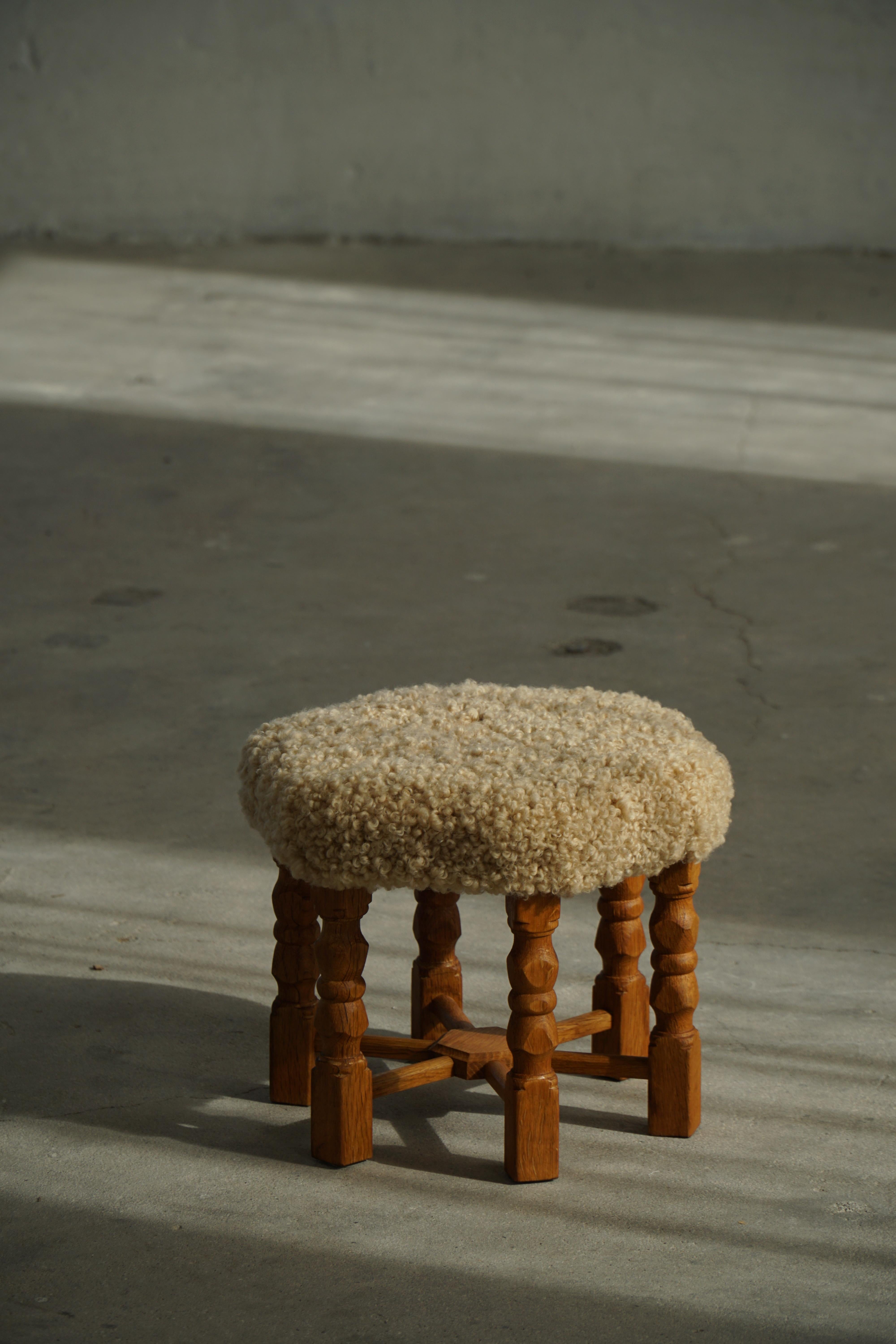 Dieser elegante Hocker aus Eichenholz mit seiner markanten sechseckigen Sitzfläche und den fein geschnitzten Beinen ist ein Beispiel für das Design der dänischen Moderne. Er ist mit luxuriöser, weicher, cremefarbener Lammwolle gepolstert. Das von