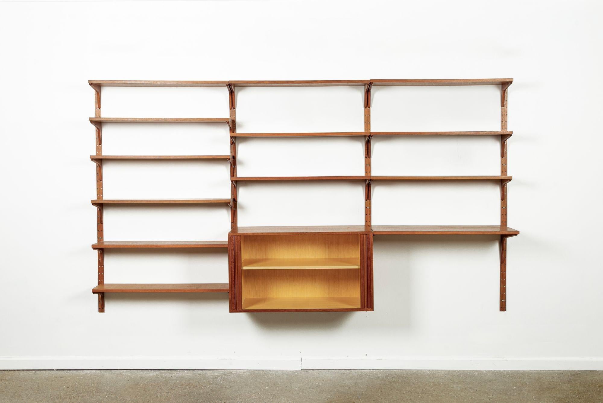 This vintage mid century Danish modern Hansen & Guldborg modular teak wood wall unit shelving system and bookcase was made in Denmark circa 1960. The classic Scandinavian modern design features clean, minimalist lines and is well-crafted from teak