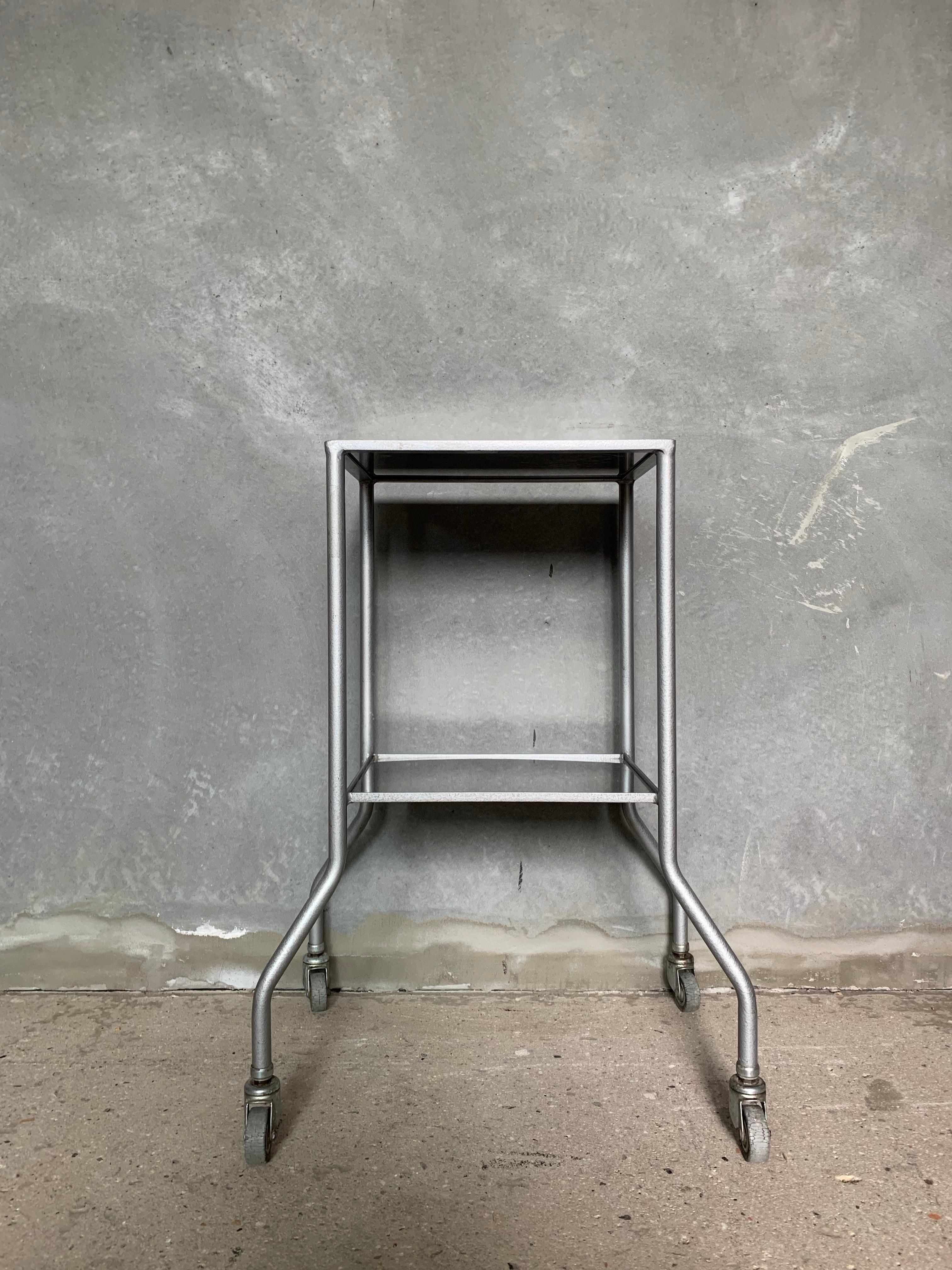 Small size industrial medical table featuring two shelves - stands on castors.