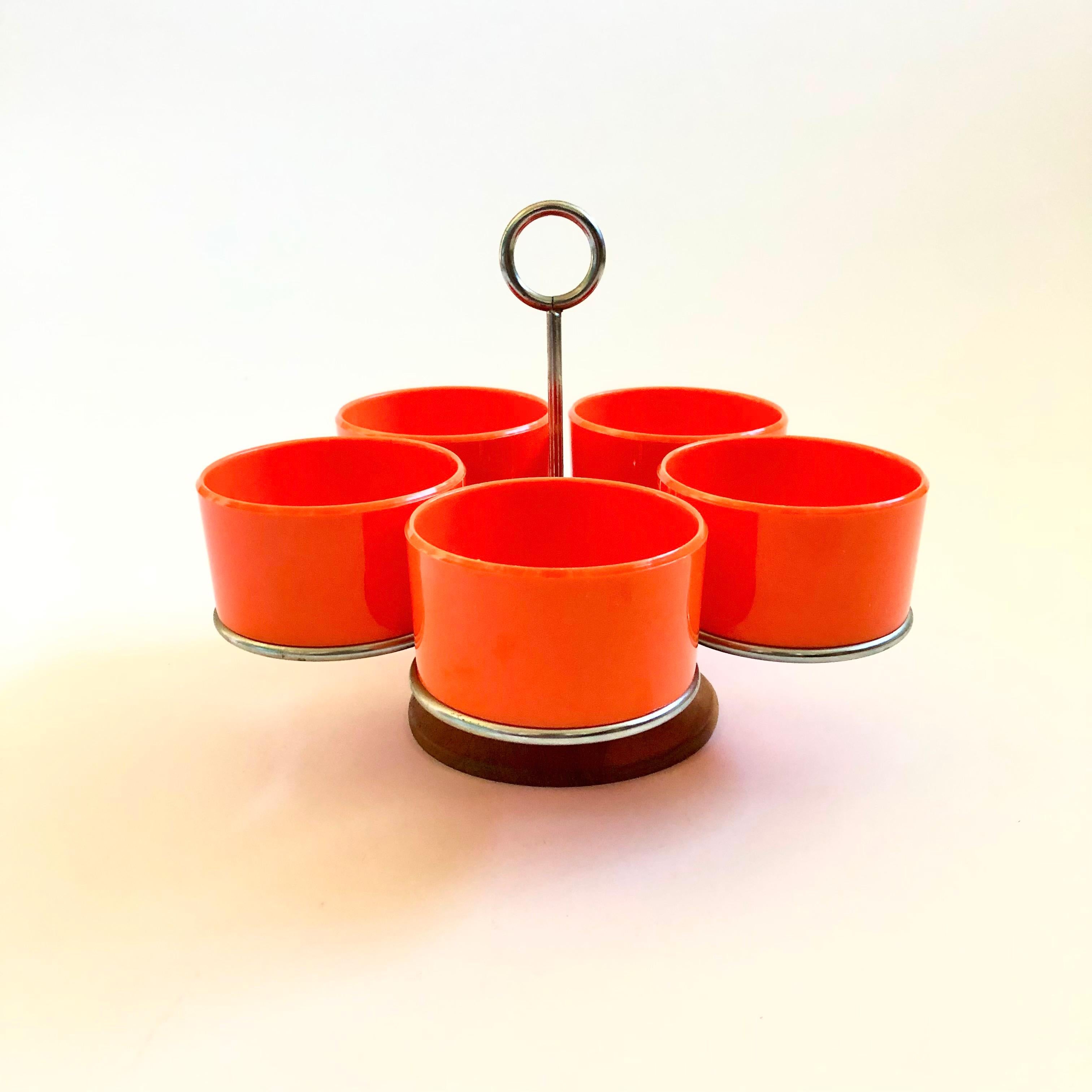 A vintage mid century serving set. Includes 5 small bowls made out of plastic in a vibrant orange color. The bowls are held in a rotating wood base with a metal handle. Perfect for serving sauces, condiments, or snacks. Made in Denmark by Luthje
