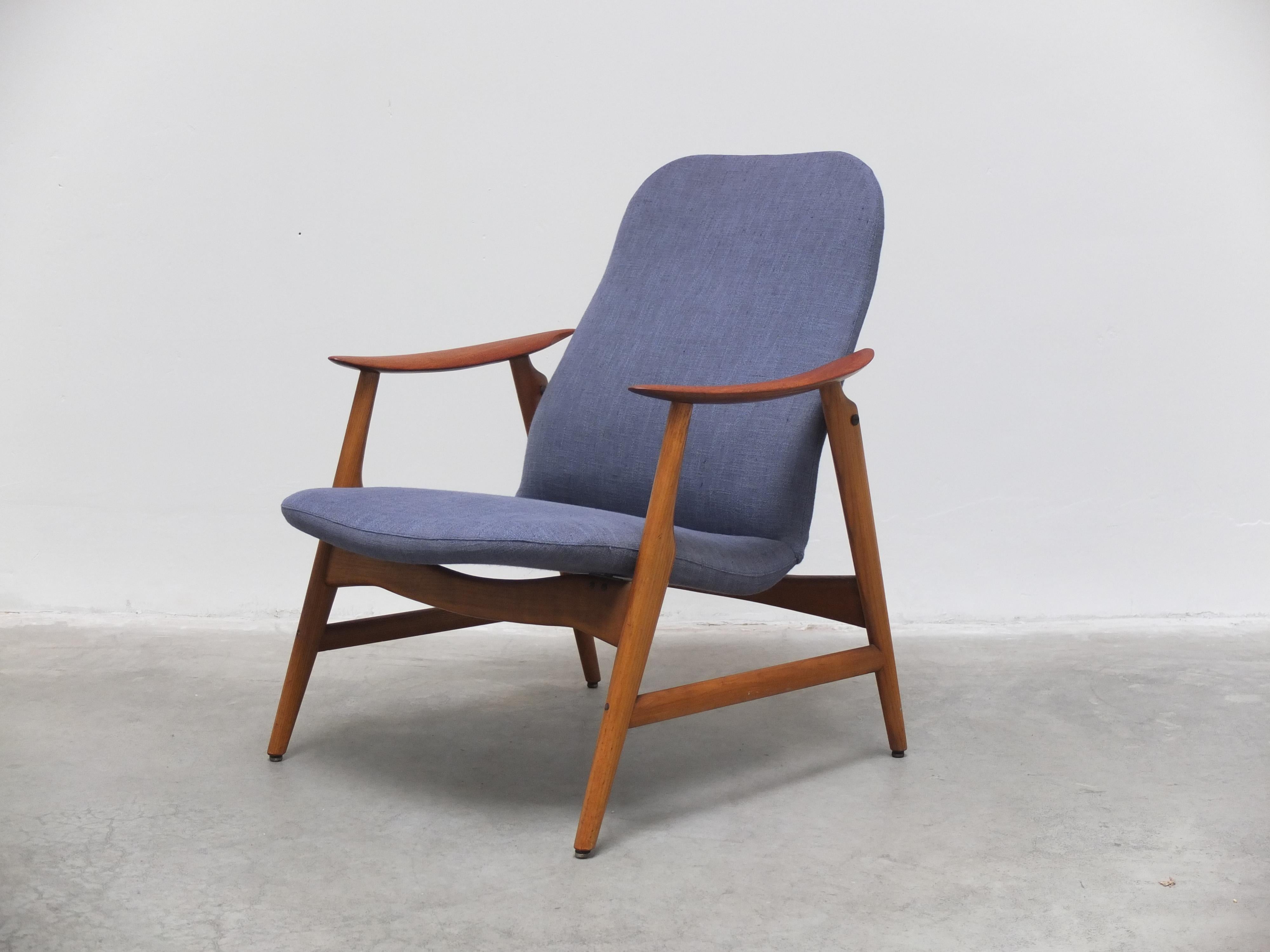 Great looking semi high-back lounge chair produced in Denmark during the 1960s. This chair has a solid teak frame with beautiful sculpted armrests and brass joints. It still has the original funky blue fabric in very good condition. Designer