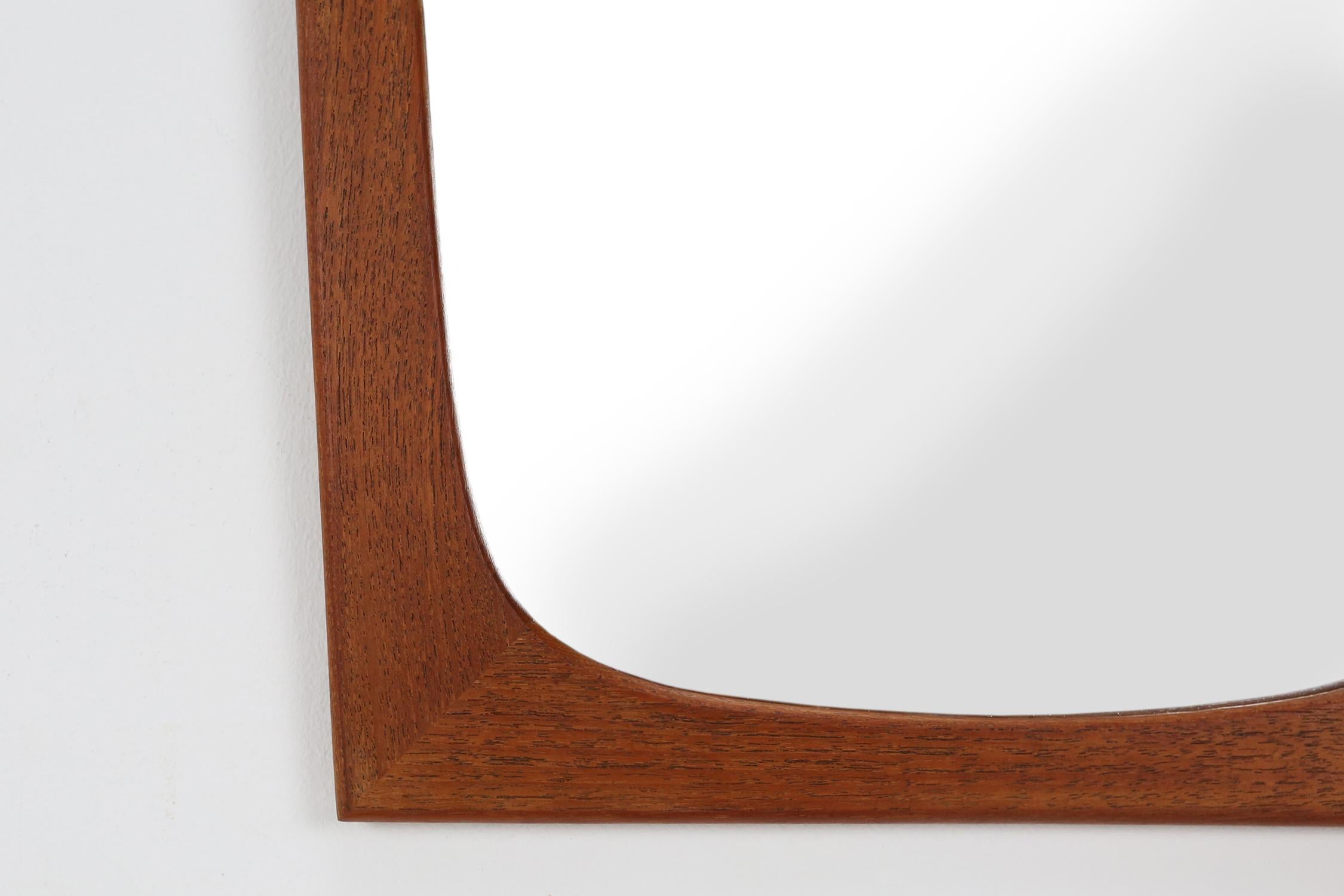 The mirror was manufactured in Denmark in the 1960s and has an original teak frame that surrounds the mirror. It is characterized by a minimalist form.