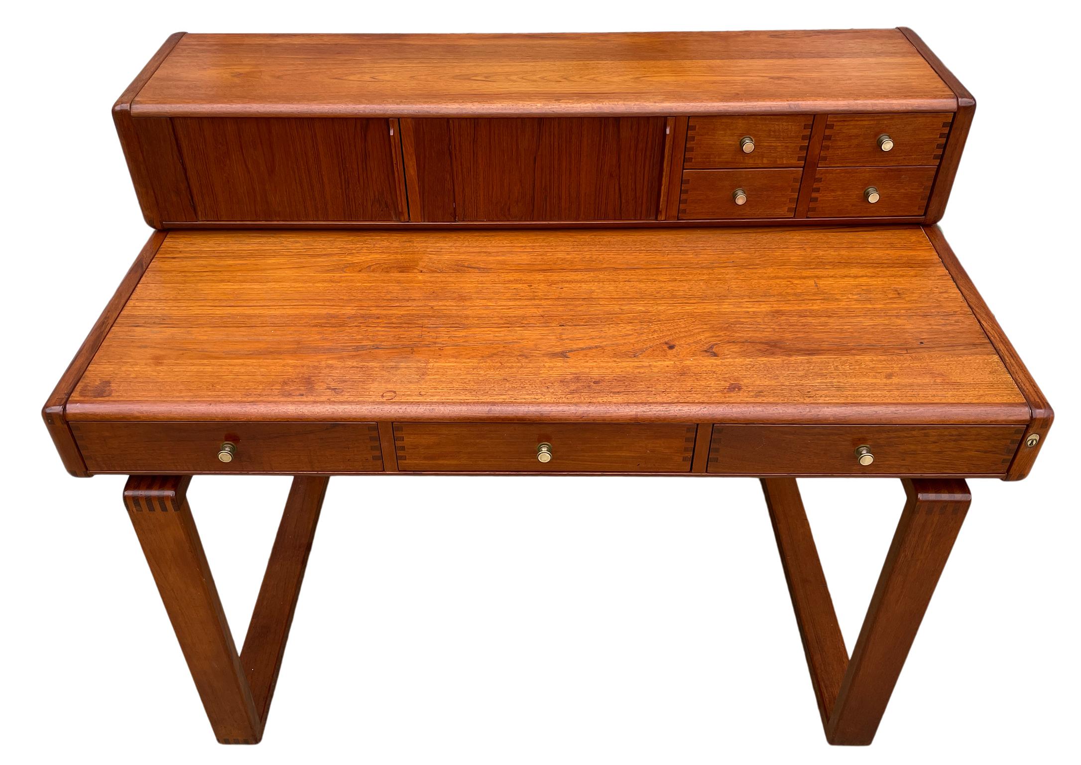 Mid century Danish modern teak desk with top organizer that has 4 drawers (2 locking) and 2 small tambour storage cabinets. The lower section of the desk has 3 drawers with (1) locking drawer on the right side. Beautiful Teak desk Made by D Scan.