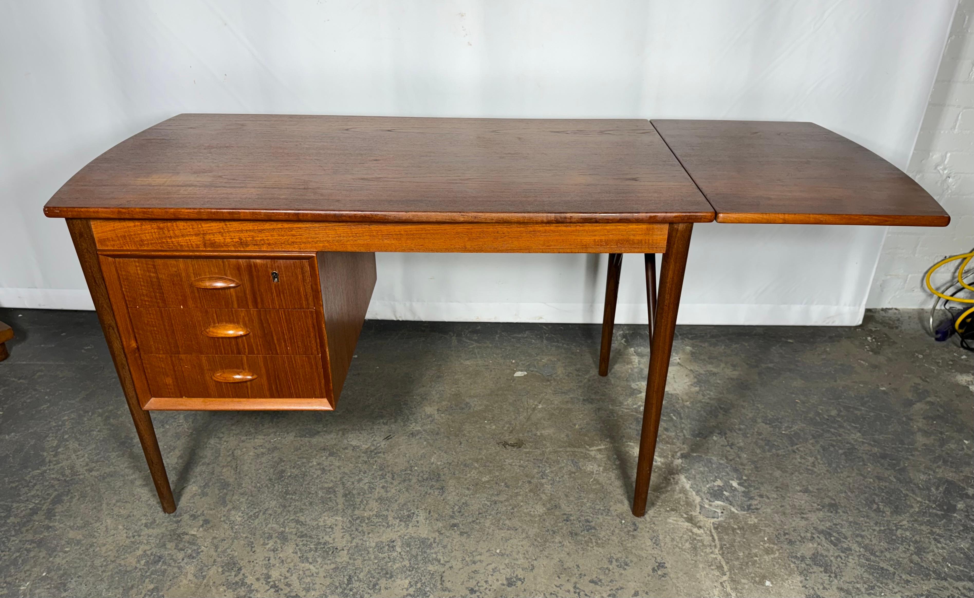 Mid Century Danish Modern Teak Drop Leaf Desk / Denmark.Designed by aRNE Vodder.. classic desk with 3 drawer and 1 removable extension leaf on the right side..Measures 64.5 w when extended. Minor dark spots and fading to top.. tiny veneer chip to