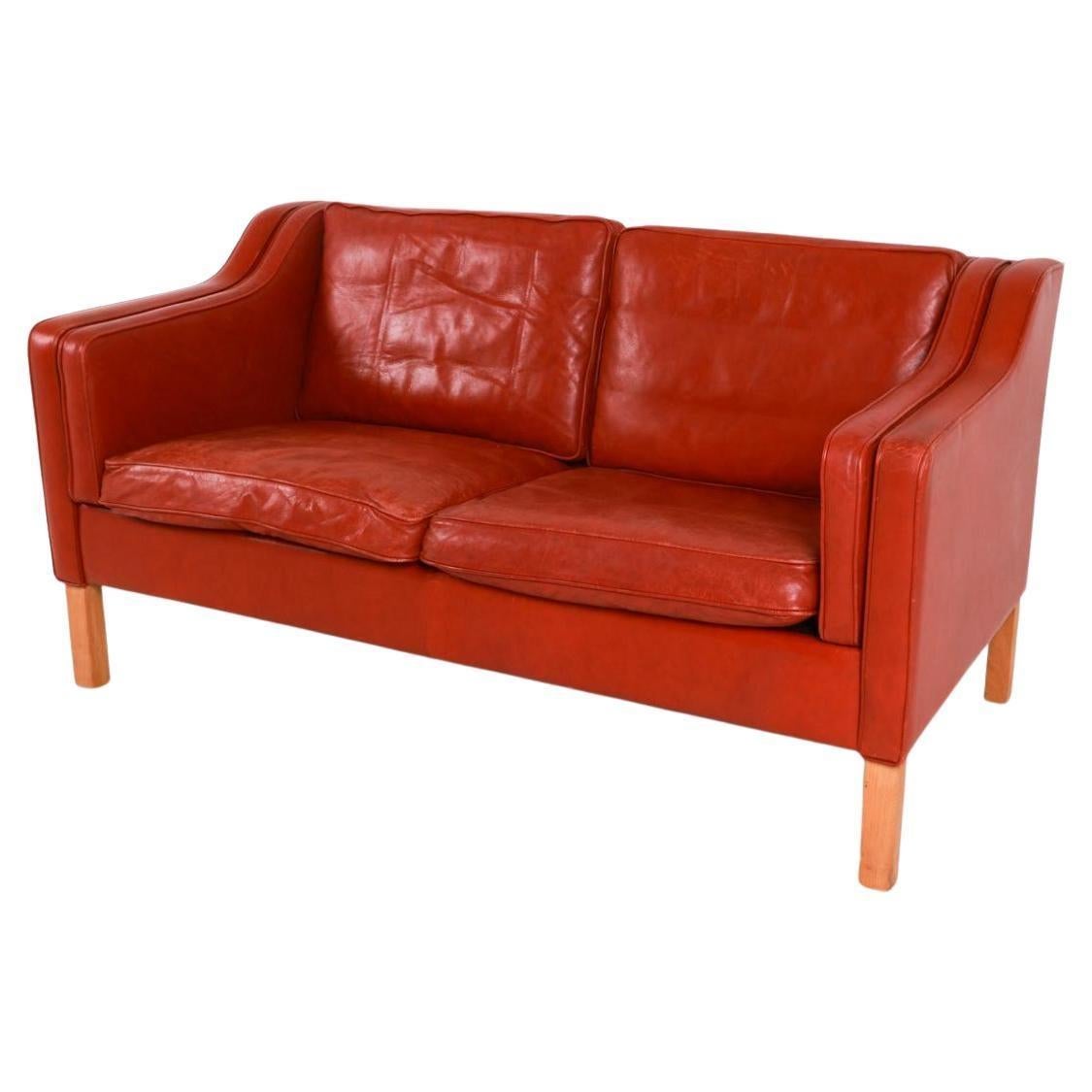 Moderne danois du milieu du siècle magnifique loveseat en cuir rouge foncé canapé pieds en bouleau. Conçu par Mogens Hansen. Le cuir rouge foncé est souple et présente des signes d'utilisation, mais il est bien rodé. Superbe petit canapé moderne