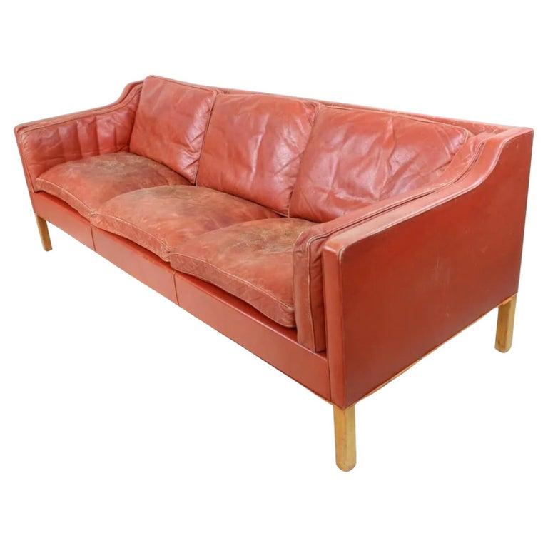 Divano a 3 posti in pelle rossa sbiadita e usurata, gambe in legno di betulla. Disegnato da Børge Mogensen Realizzato da Fredericia Stolefabrik. La bella pelle rossa è sbiadita e mostra un sacco di patina/usura morbida e ben rodata. Ha tutti i